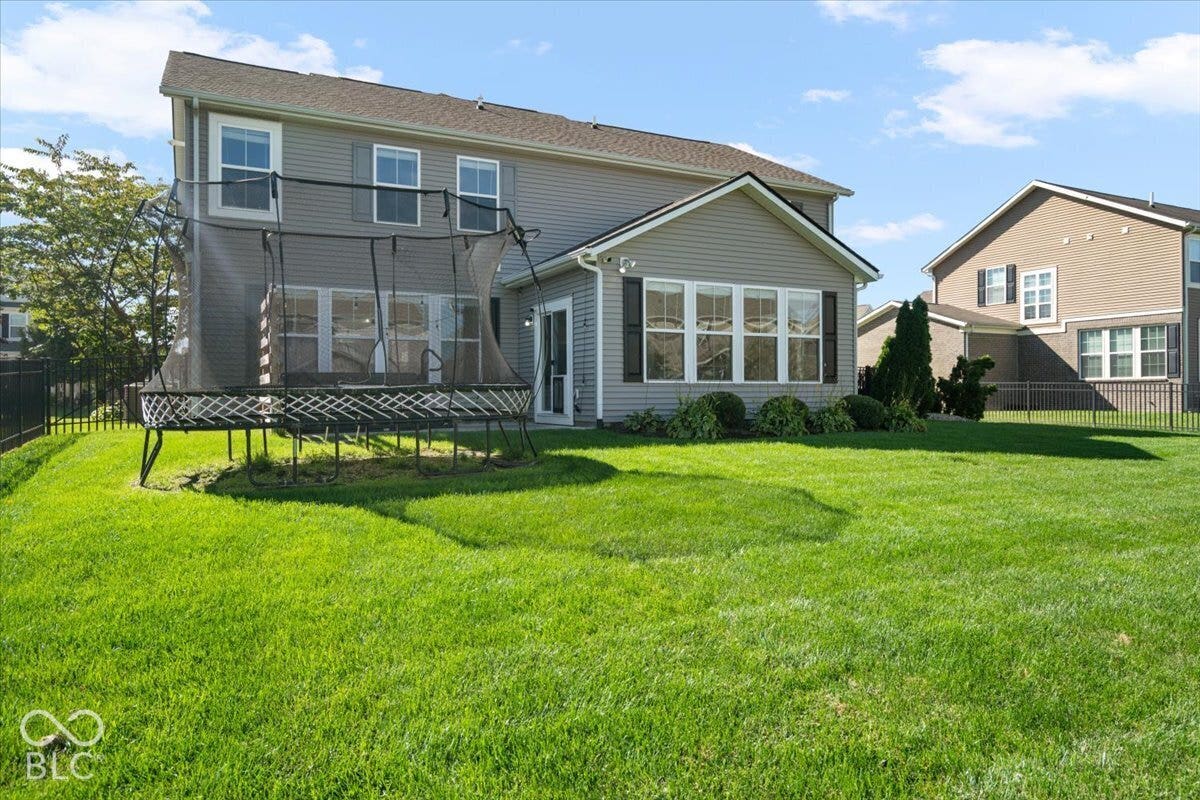 5570 W Stream Drive, McCordsville, IN 46055 Expansive rear yard featuring a manicured lawn, full fencing, and a sunroom addition with multiple windows