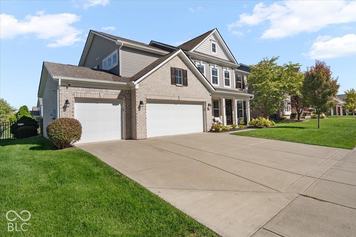 5570 W Stream Drive, McCordsville, IN 46055 Light-colored brick and siding exterior, two attached garage doors, concrete driveway, and established front landscaping