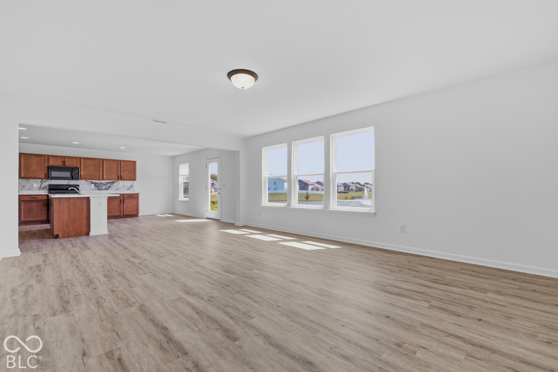 10525 Broadford Street, Indianapolis, IN 46239 Expansive main living area featuring wood-finish flooring, multiple windows, and a flush-mount ceiling light