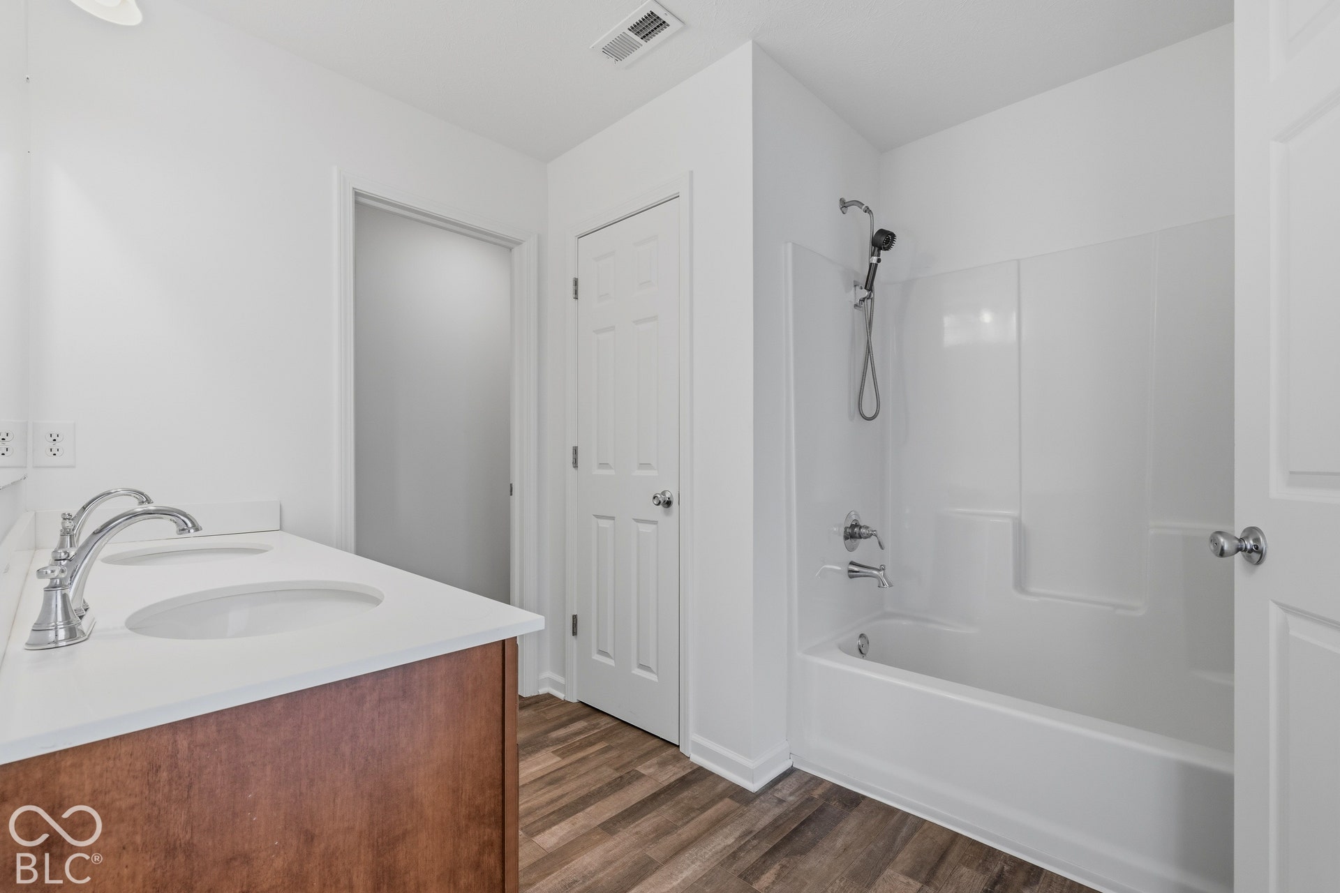 10525 Broadford Street, Indianapolis, IN 46239 Dual vanity with white countertop, wood-finish cabinetry, chrome fixtures, and wood-finish flooring
