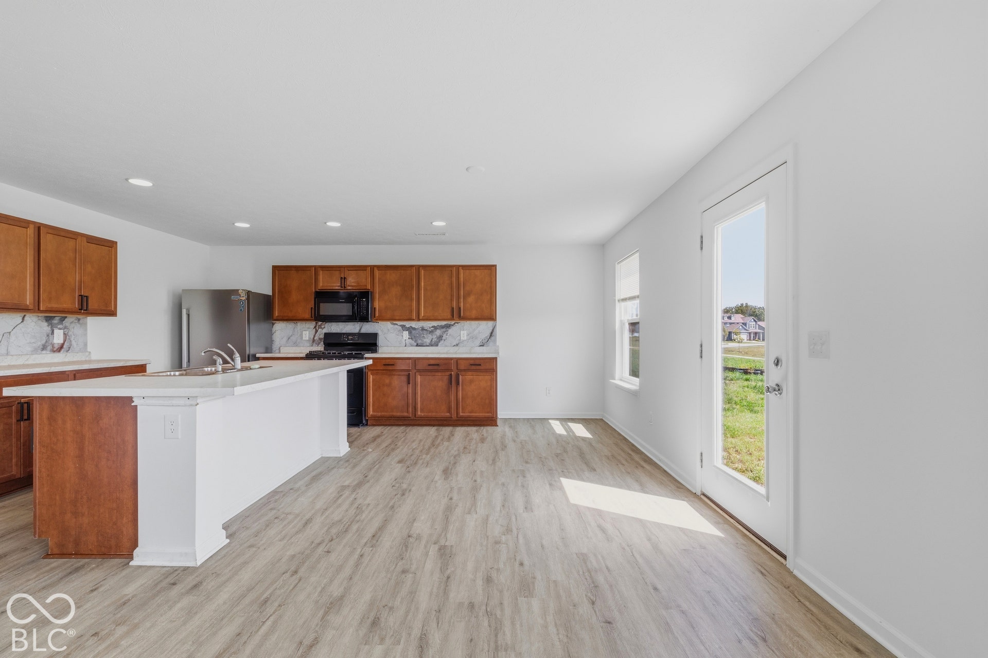 10525 Broadford Street, Indianapolis, IN 46239 Kitchen with wood cabinetry, stainless steel appliances, a center island with sink, and wood-finish flooring