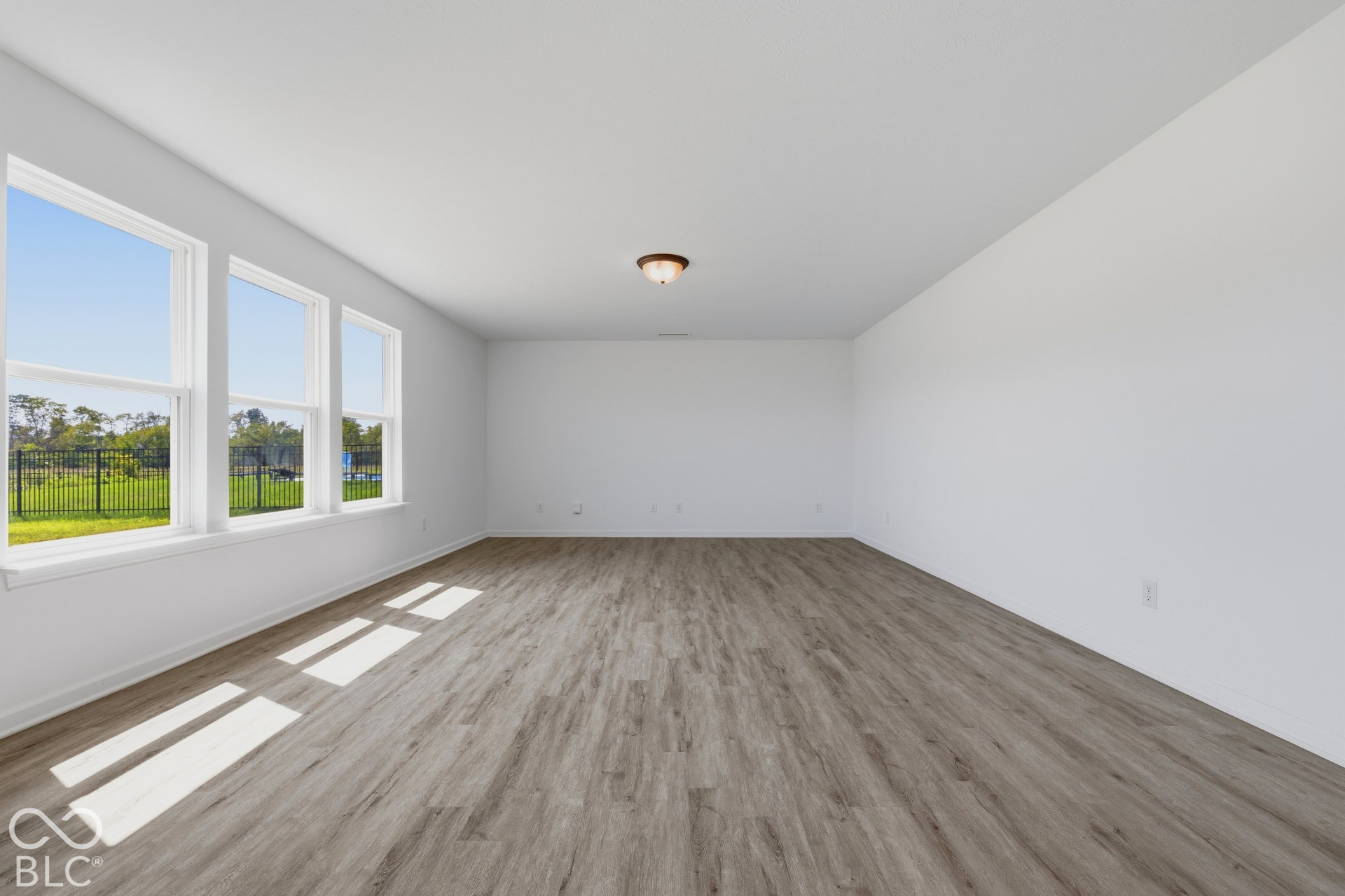 10525 Broadford Street, Indianapolis, IN 46239 Expansive room featuring wood-finish flooring, multiple windows, and a flush-mount ceiling light