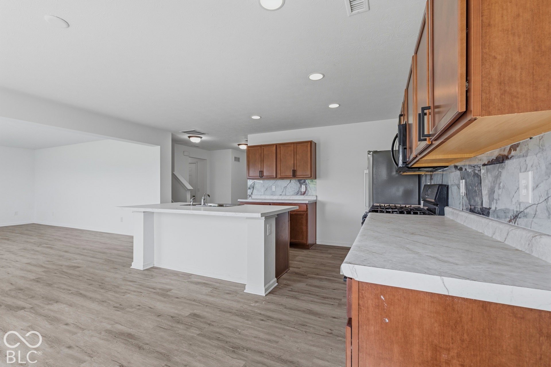 10525 Broadford Street, Indianapolis, IN 46239 Kitchen featuring wood-finish flooring, recessed lighting, and a kitchen island with an integrated sink