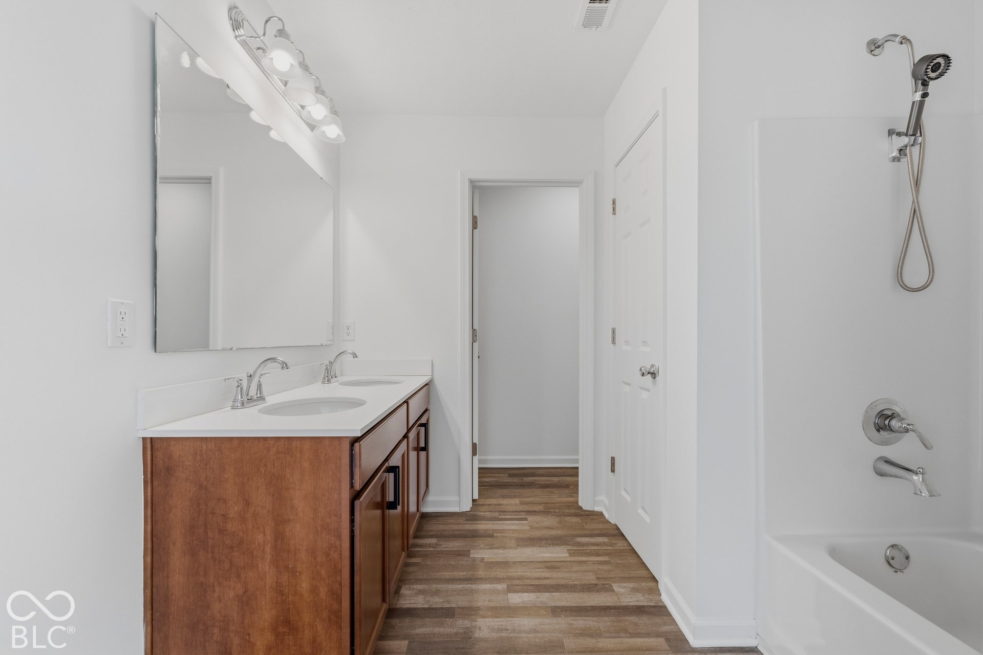 10525 Broadford Street, Indianapolis, IN 46239 Dual vanity with wood-finish cabinetry and chrome fixtures, ample counter space, integrated bathtub, and wood-finish flooring