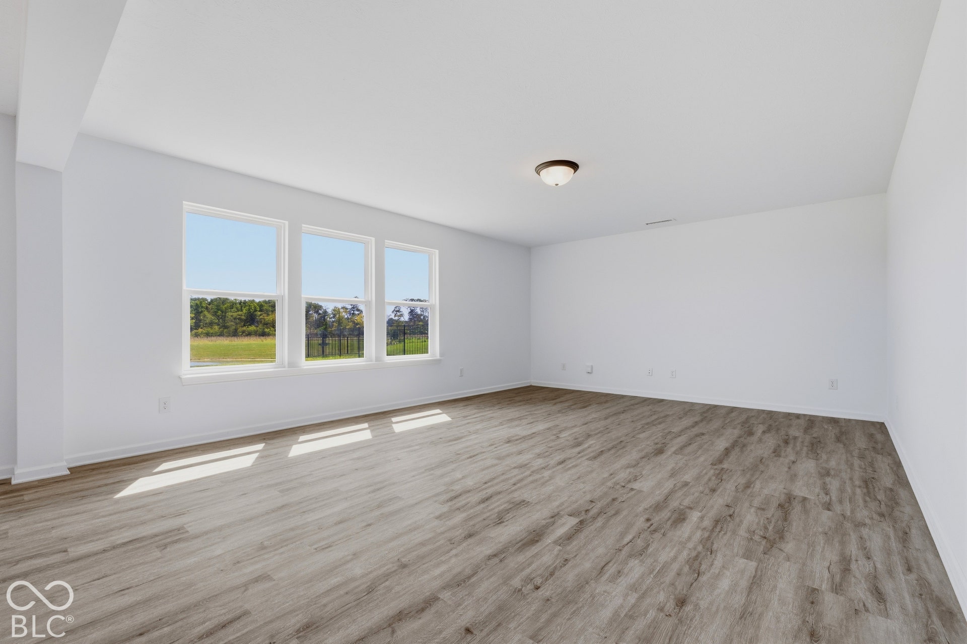 10525 Broadford Street, Indianapolis, IN 46239 Spacious room with wood-finish flooring, white walls, and a series of three large windows