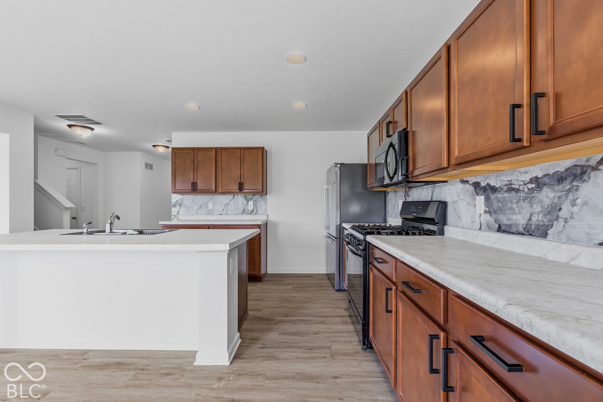 10525 Broadford Street, Indianapolis, IN 46239 Kitchen featuring wood-finish flooring, white countertops, wood cabinetry with black hardware, and a stone backsplash