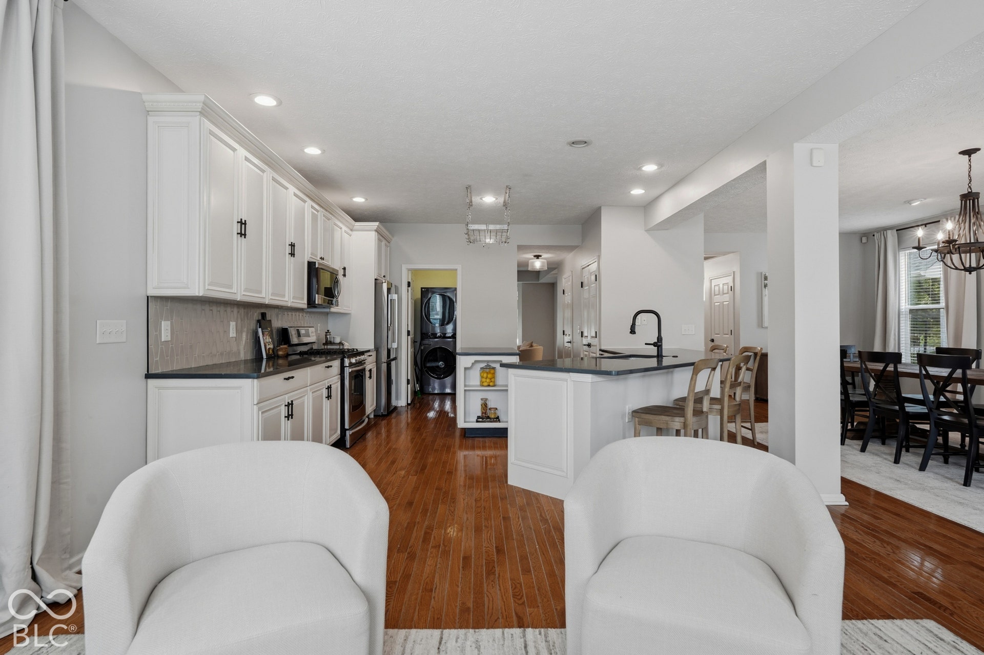 Open-concept kitchen featuring white cabinetry, black countertops, and wood-finish flooring