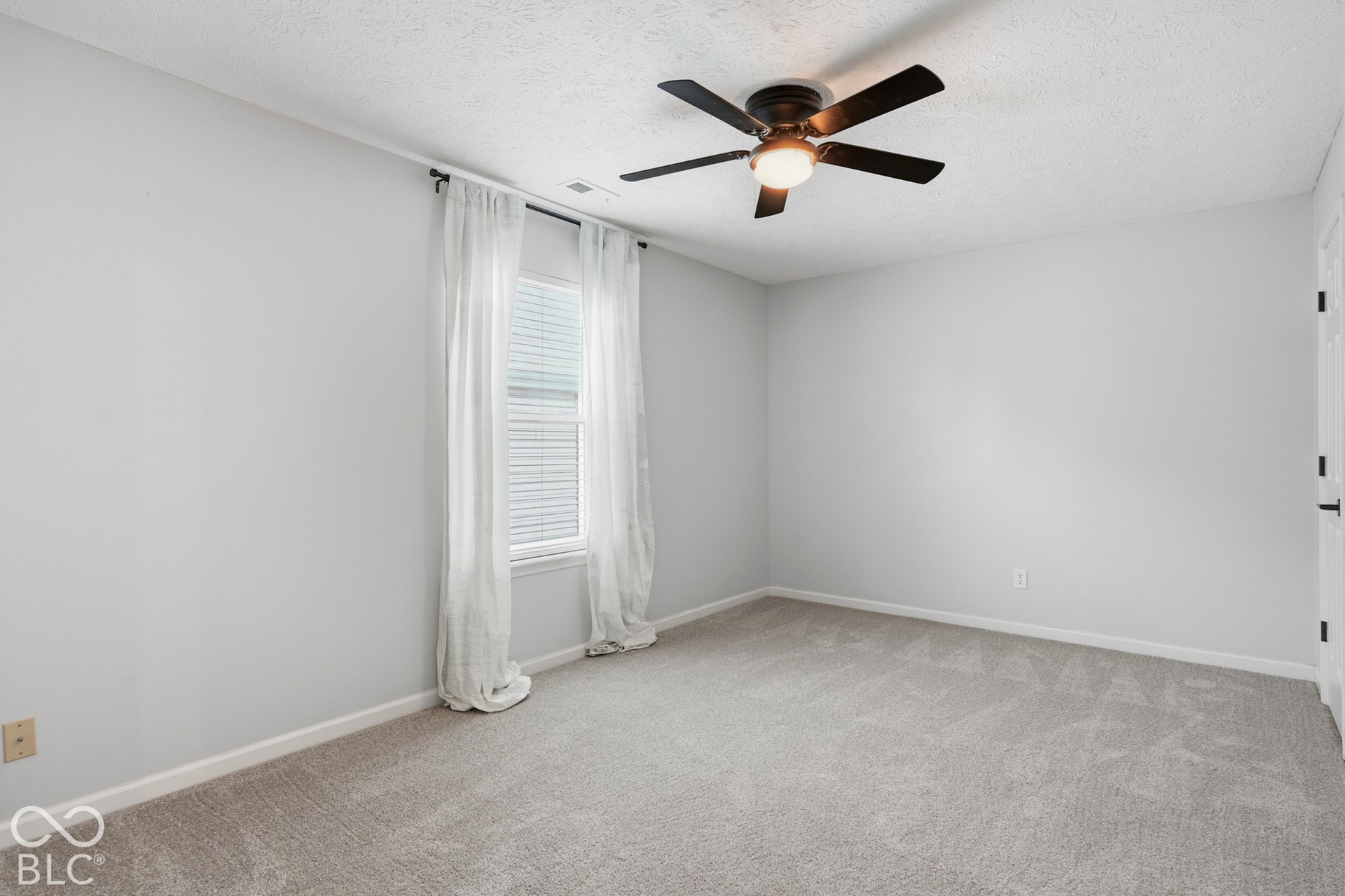 Neutral wall color, carpet flooring, window with blinds, and a ceiling fan with integrated lighting