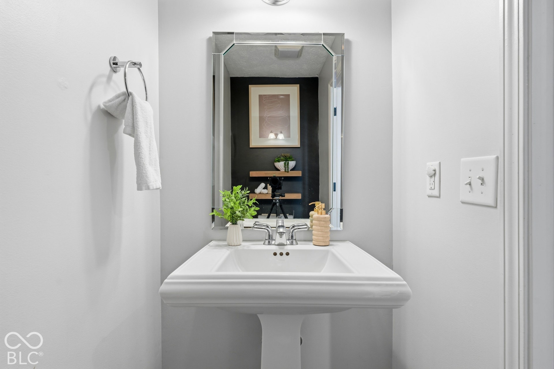 Pedestal sink with chrome faucet, mirrored vanity, and recessed lighting