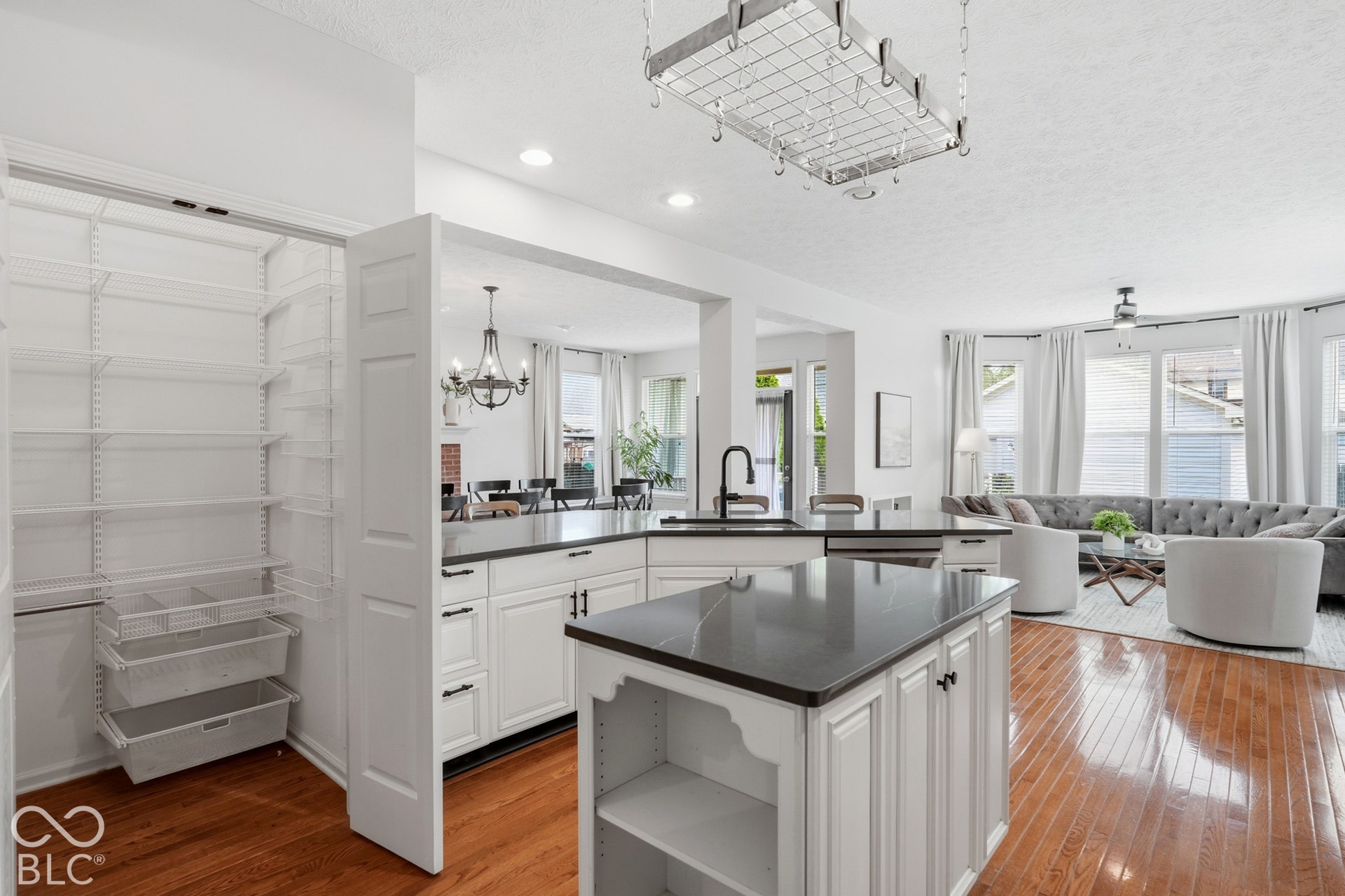 Kitchen featuring a central island, dark countertops, white cabinetry, and a pot rack