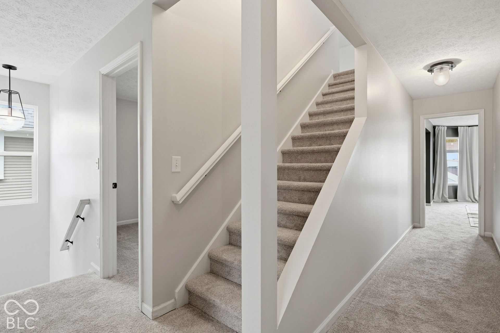 Carpeted staircase with white railing, light gray walls, and recessed lighting