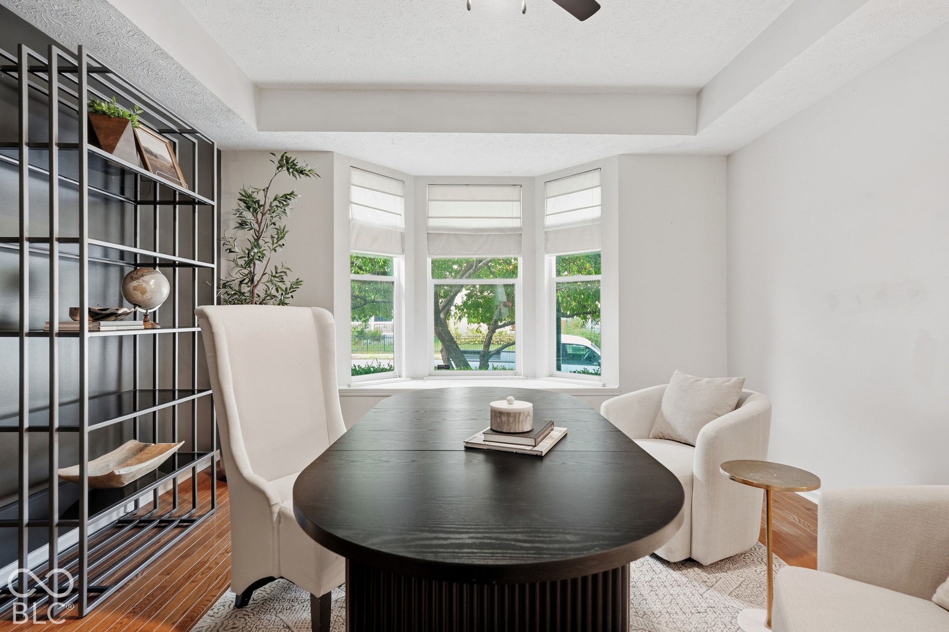 Bay window with multiple panels, hardwood flooring, built-in shelving, white walls, and a ceiling fan