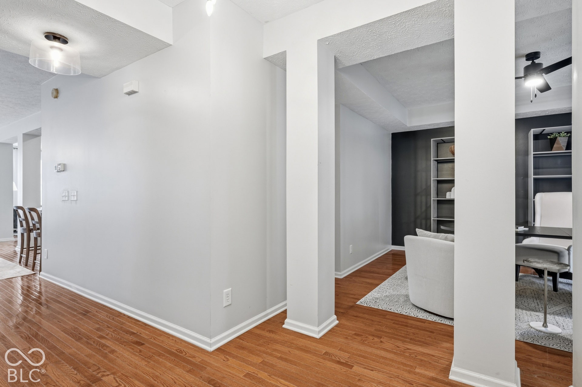 Rich hardwood flooring throughout, bright recessed lighting, and a tray ceiling in the adjacent room