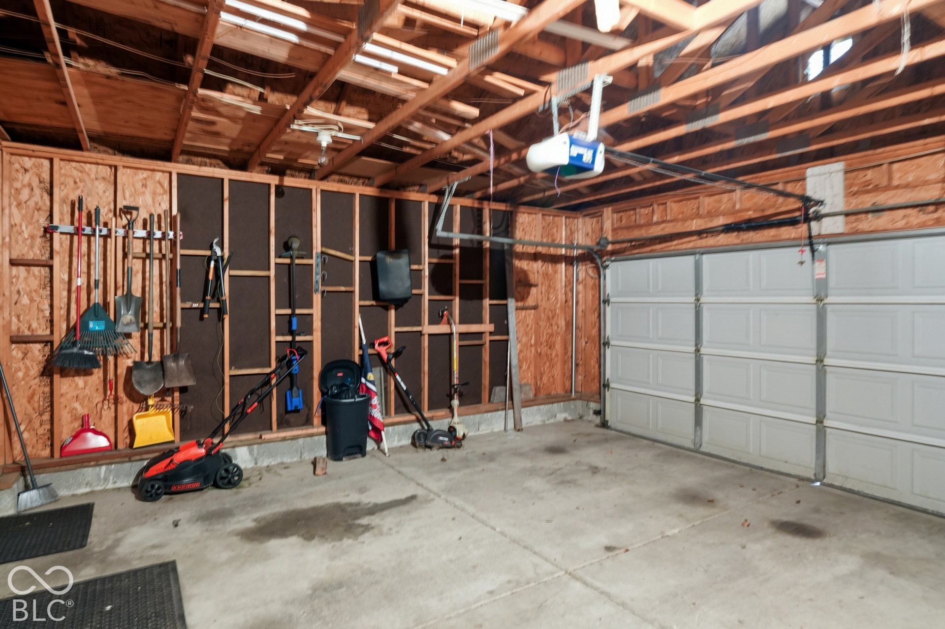 Attached garage featuring an automatic opener, exposed wood beam ceiling, and concrete flooring