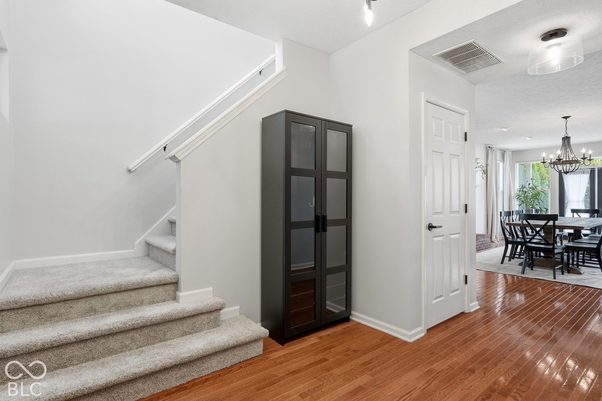 Hardwood flooring, staircase with carpeted treads, white paneled door, and recessed lighting