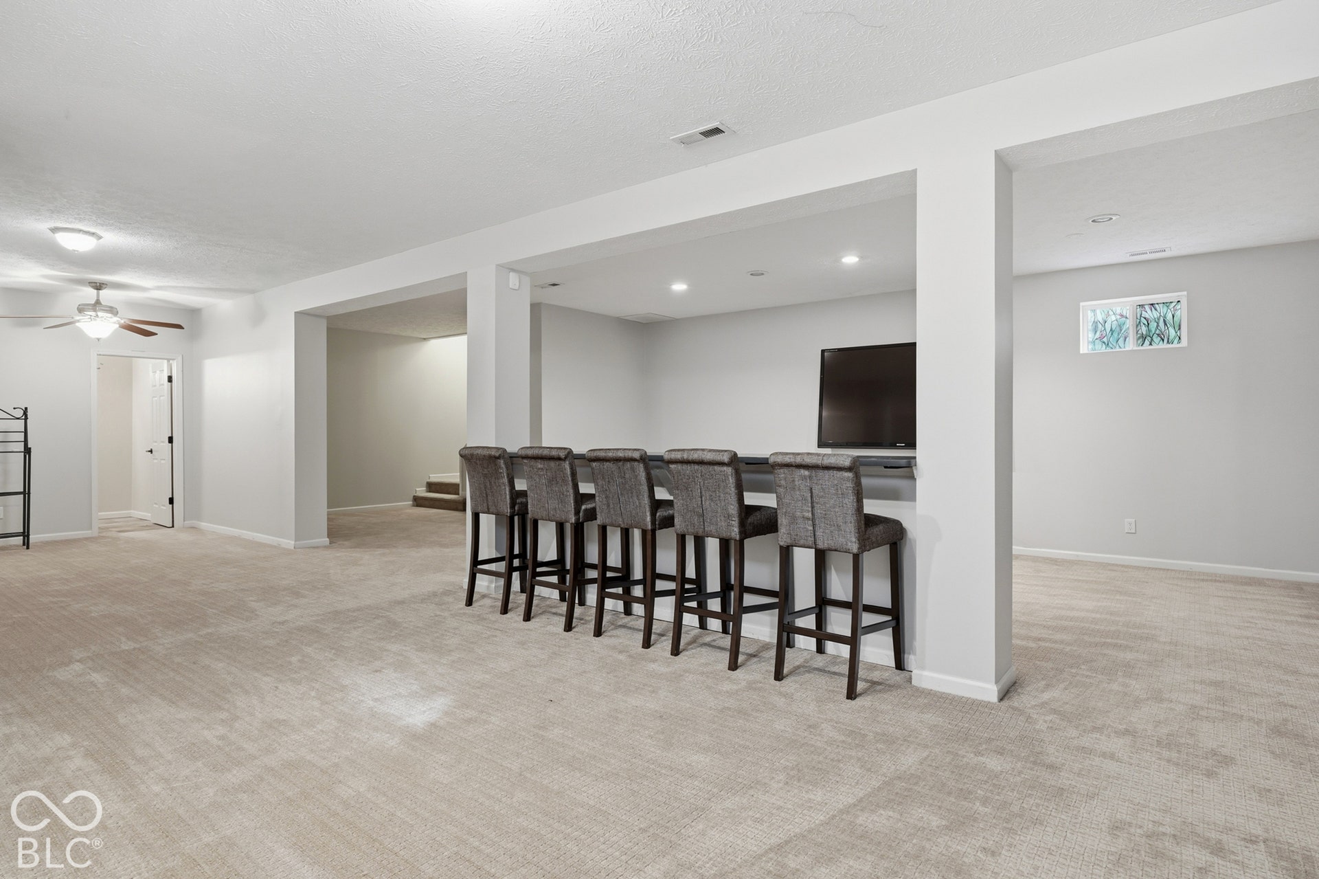 Spacious lower level featuring recessed lighting, a built-in bar, and carpeted flooring