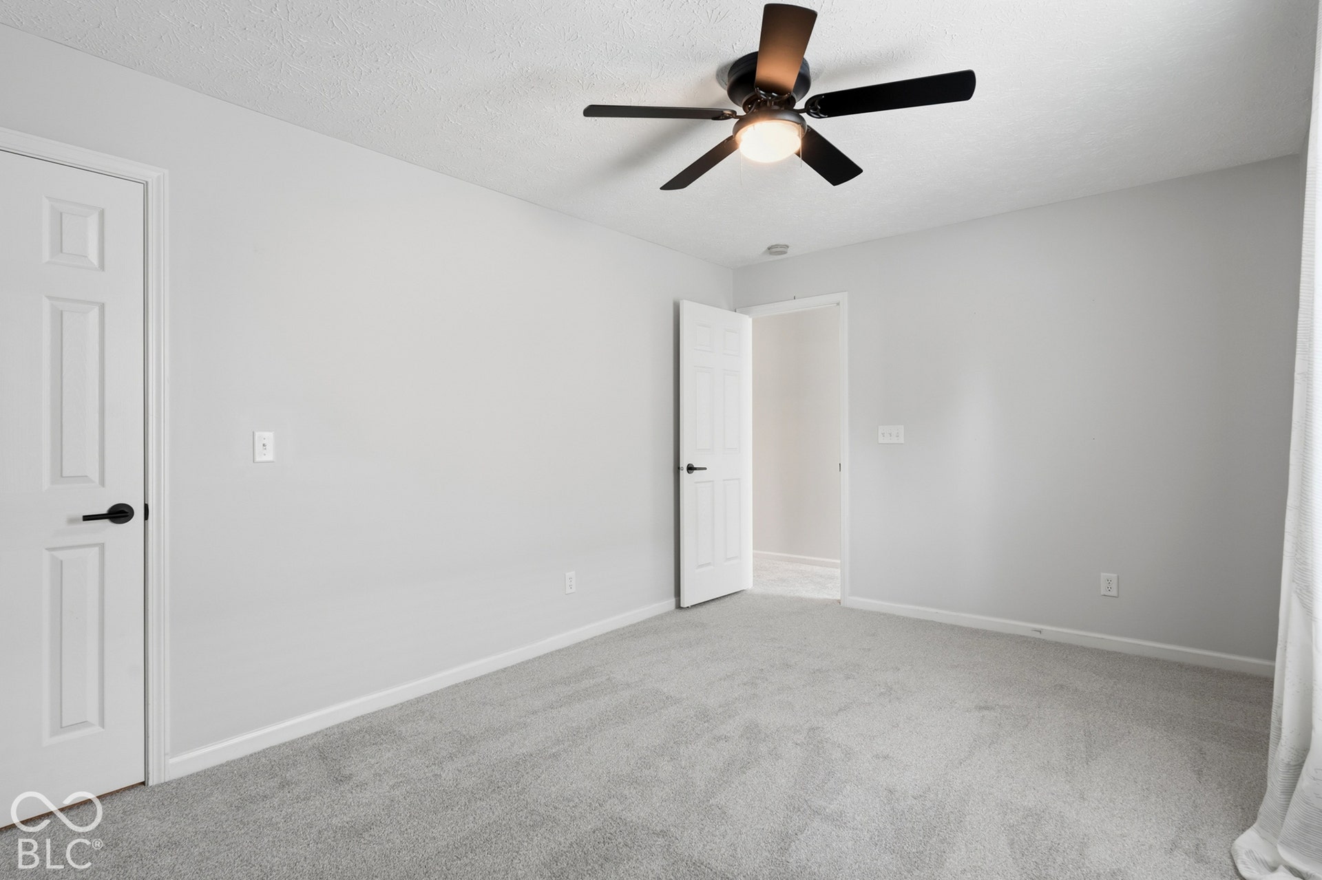 Wall-to-wall carpeting, light gray wall finishes, and a ceiling fan with integrated lighting