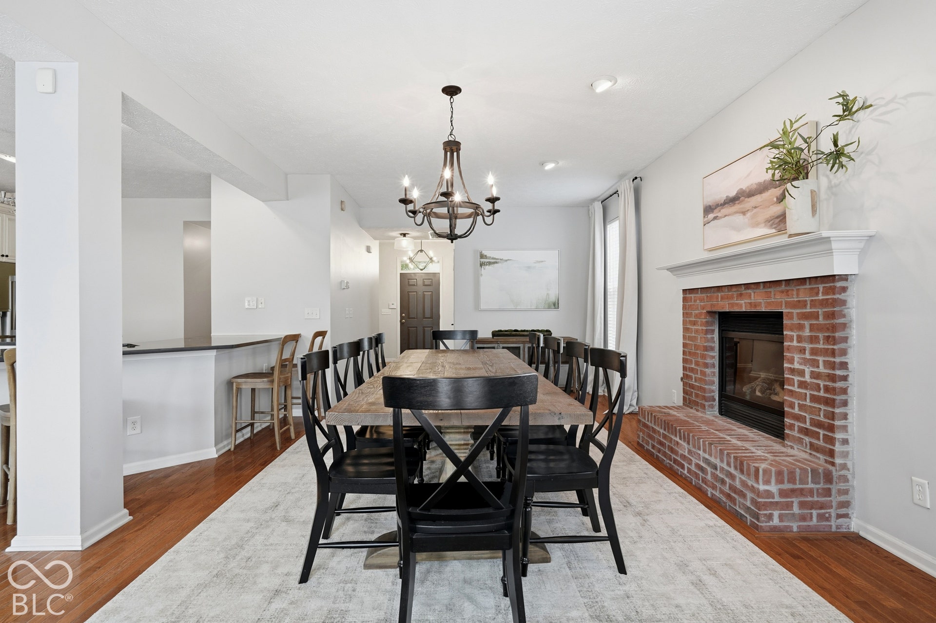 Brick fireplace with a white mantel, hardwood flooring, and a built-in breakfast bar