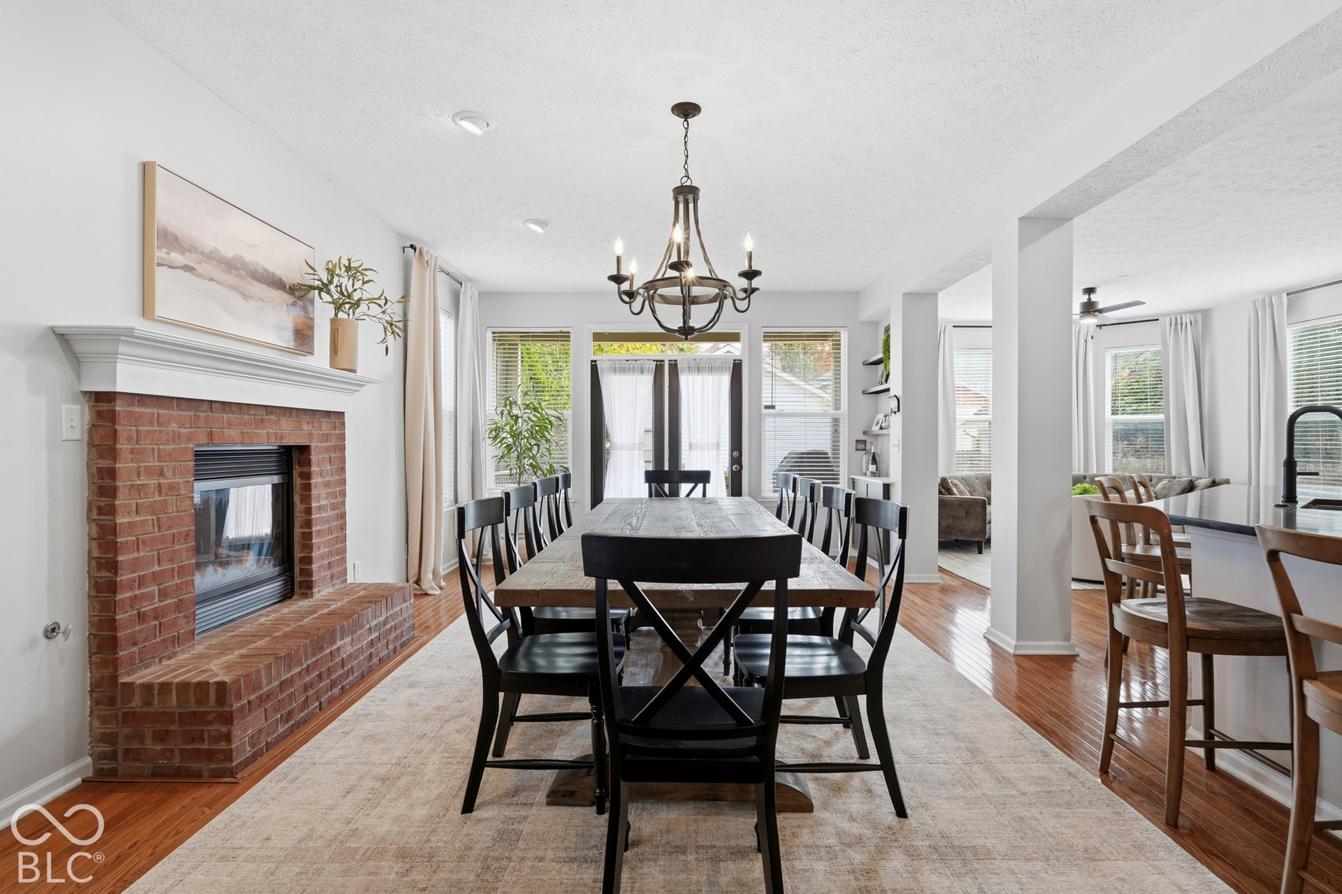 Brick-faced fireplace with a white mantel, hardwood flooring, and recessed ceiling lighting