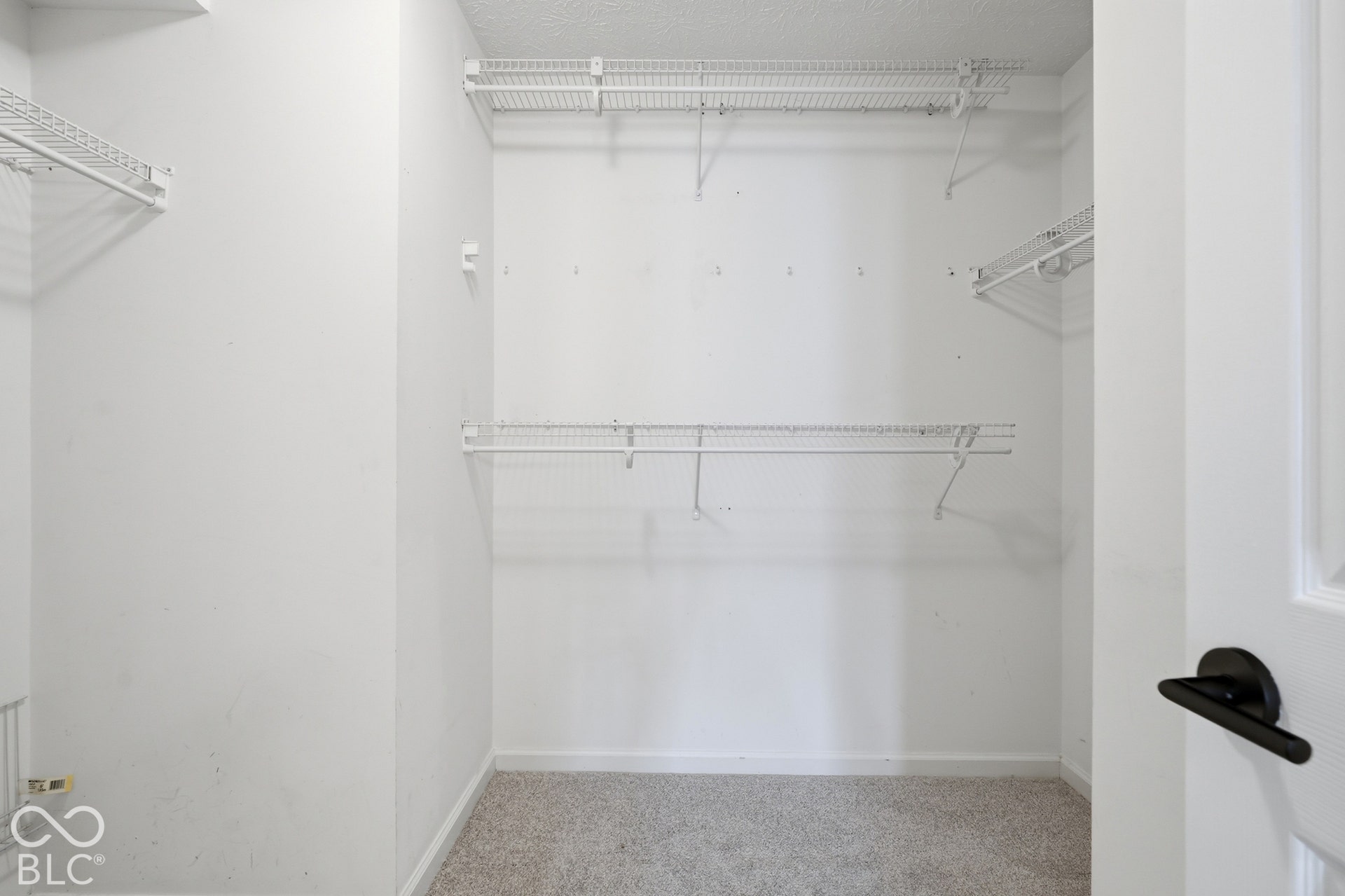 White wire shelving system, neutral carpet flooring, and white walls