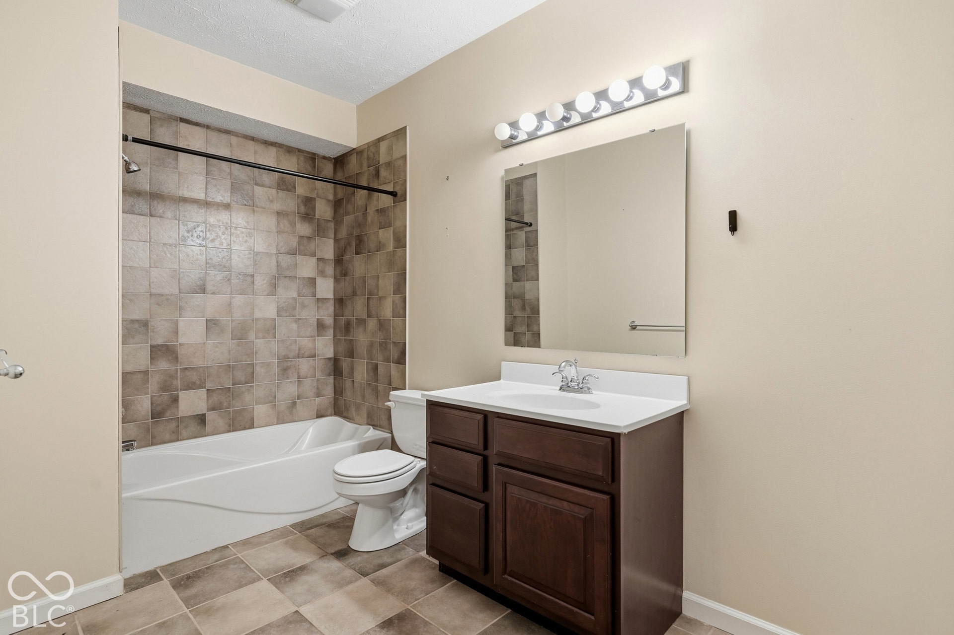 Tiled shower surround with a white bathtub and chrome fixtures