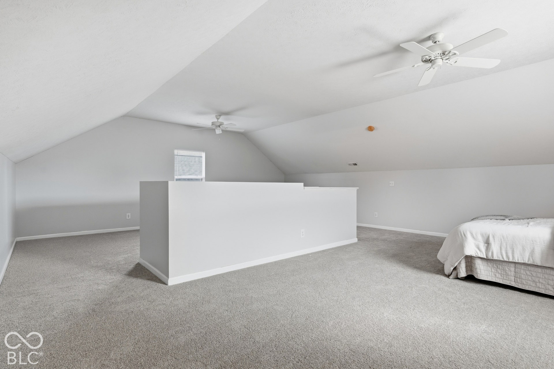 Spacious loft area featuring sloped ceilings, light gray wall paint, and gray carpet flooring