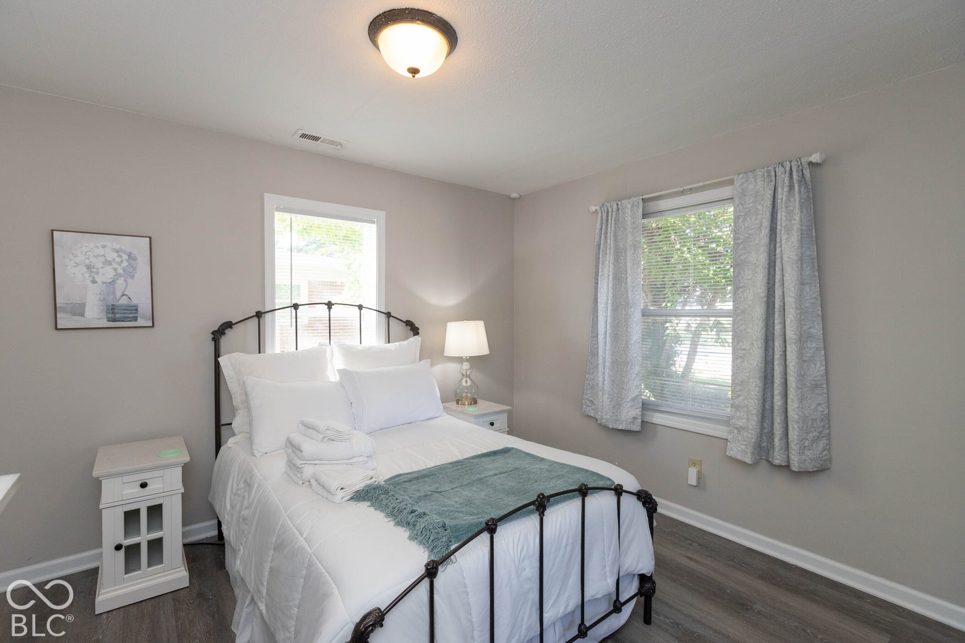 Wood-finish flooring, single window with white trim, and a semi-flush mount ceiling light