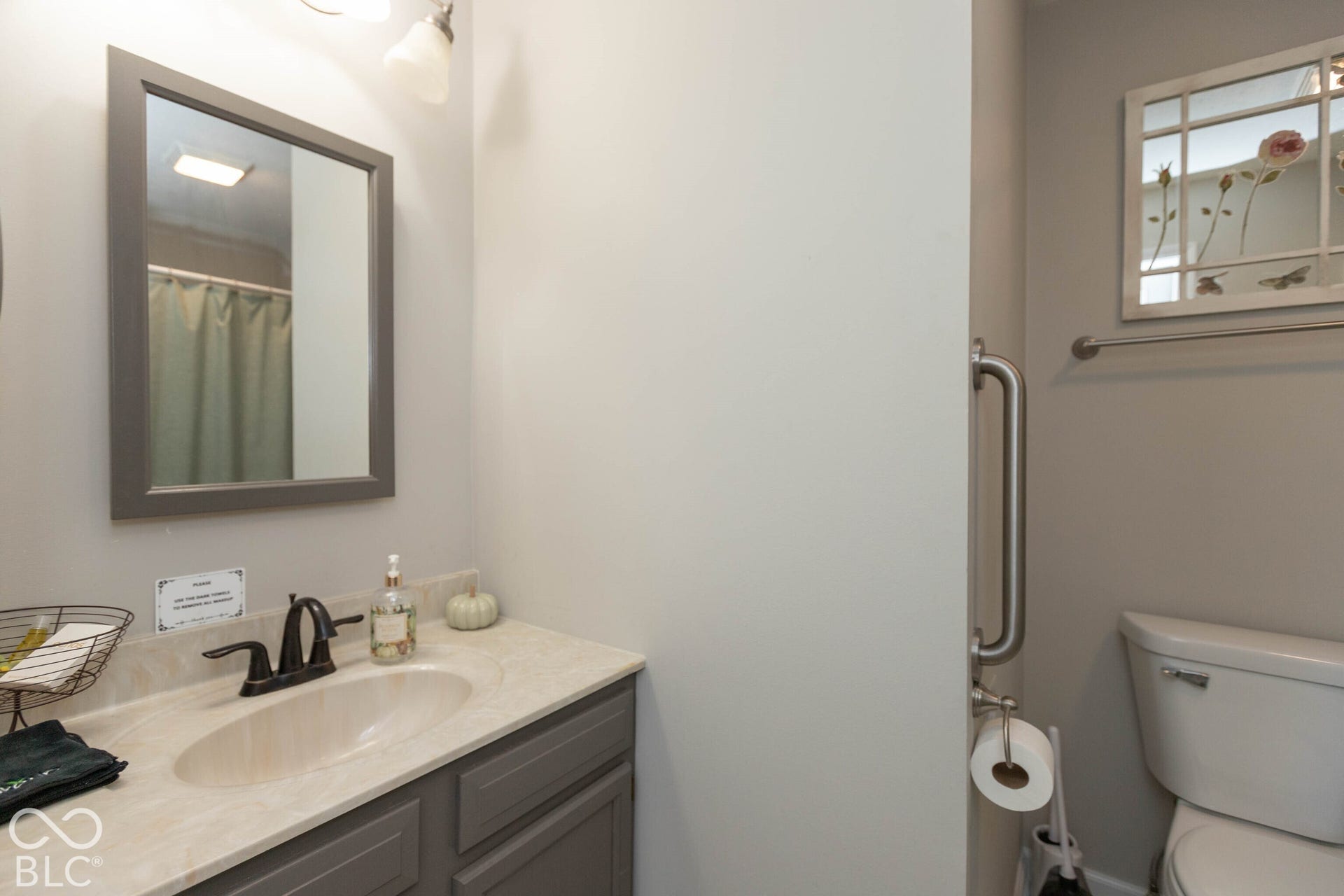 Vanity with an integrated sink, framed mirror, and a wall-mounted light fixture