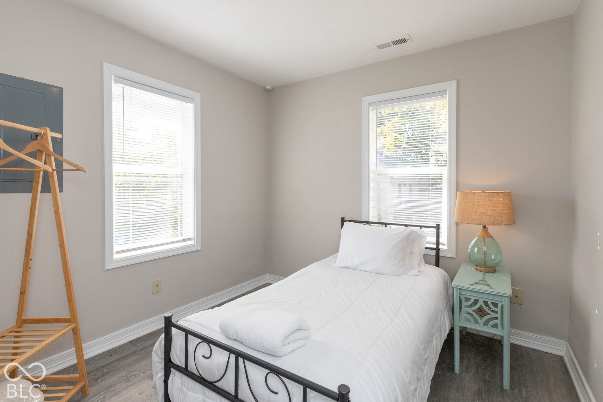 Light gray wall paint, two white-trimmed windows, gray wood-finish flooring, and white baseboards