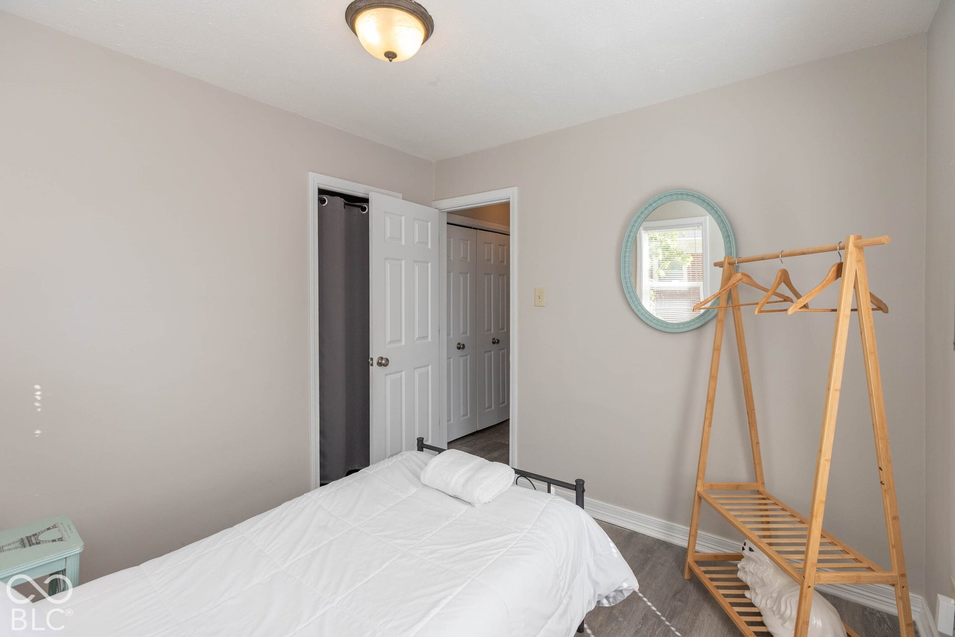 Light gray wall paint, wood-finish flooring, white trim, white paneled doors, and a flush mount ceiling light