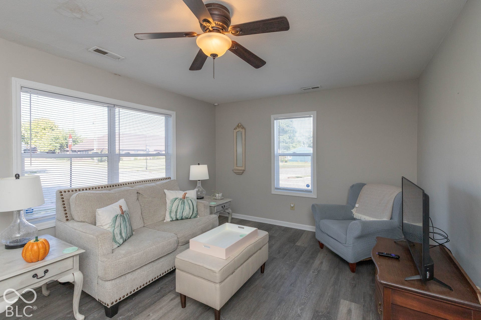 Neutral wall color, ceiling fan with integrated lighting, wood-finish flooring, and white window blinds