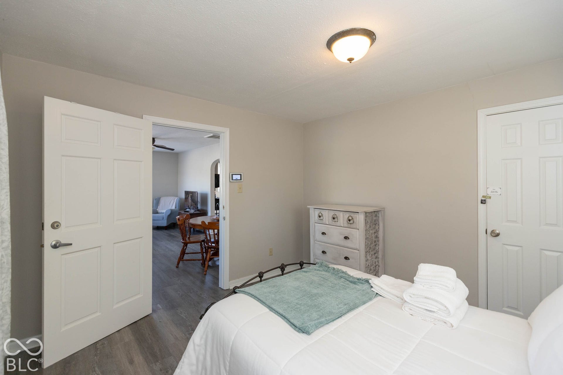 Wood-finish flooring, white paneled doors, and a flush mount ceiling light fixture