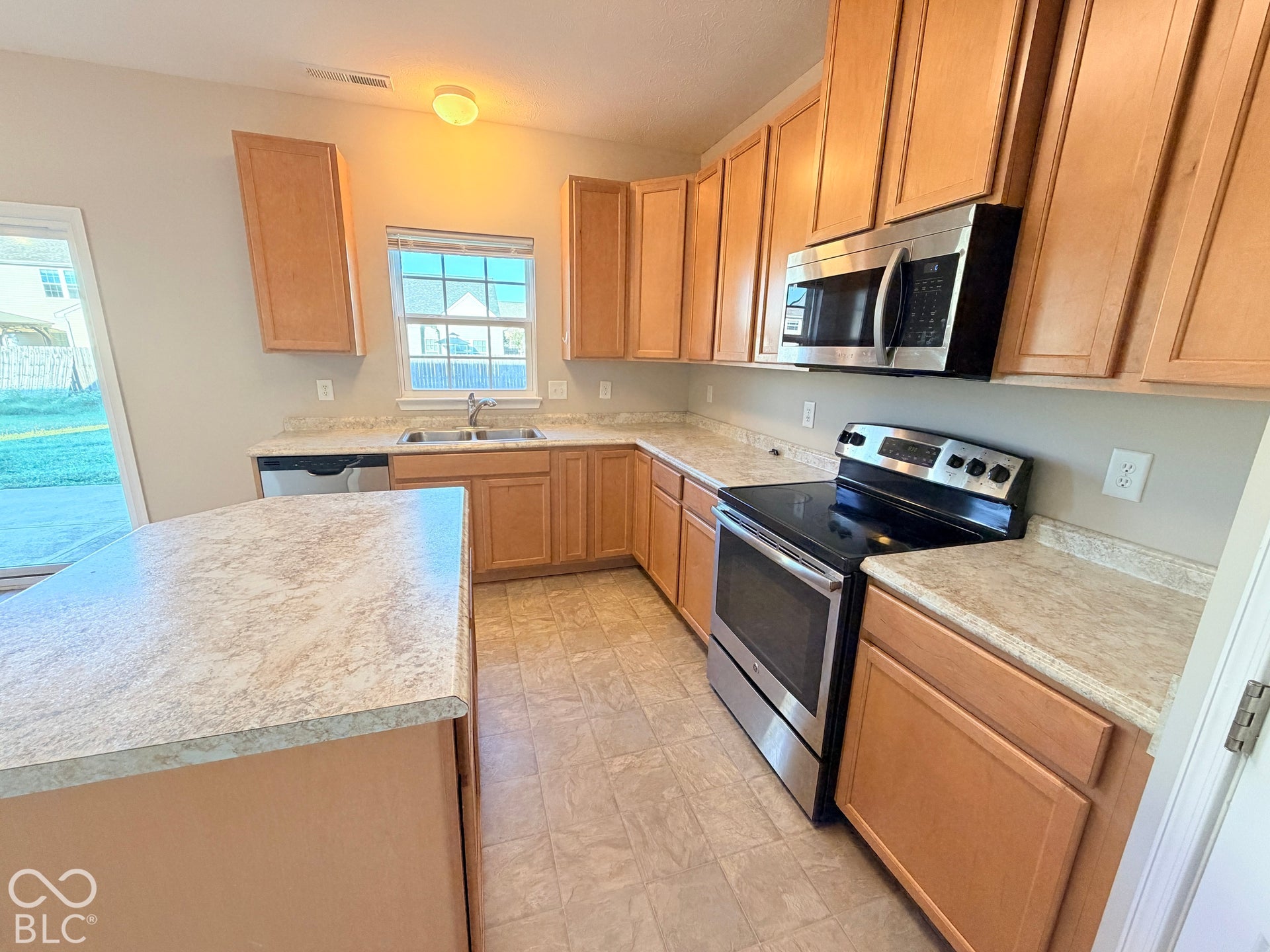652 Classic Lane, Greenwood, IN 46143 Kitchen featuring a central island, light wood-finish cabinetry, light-toned countertops, a stainless steel microwave, and a stainless steel range
