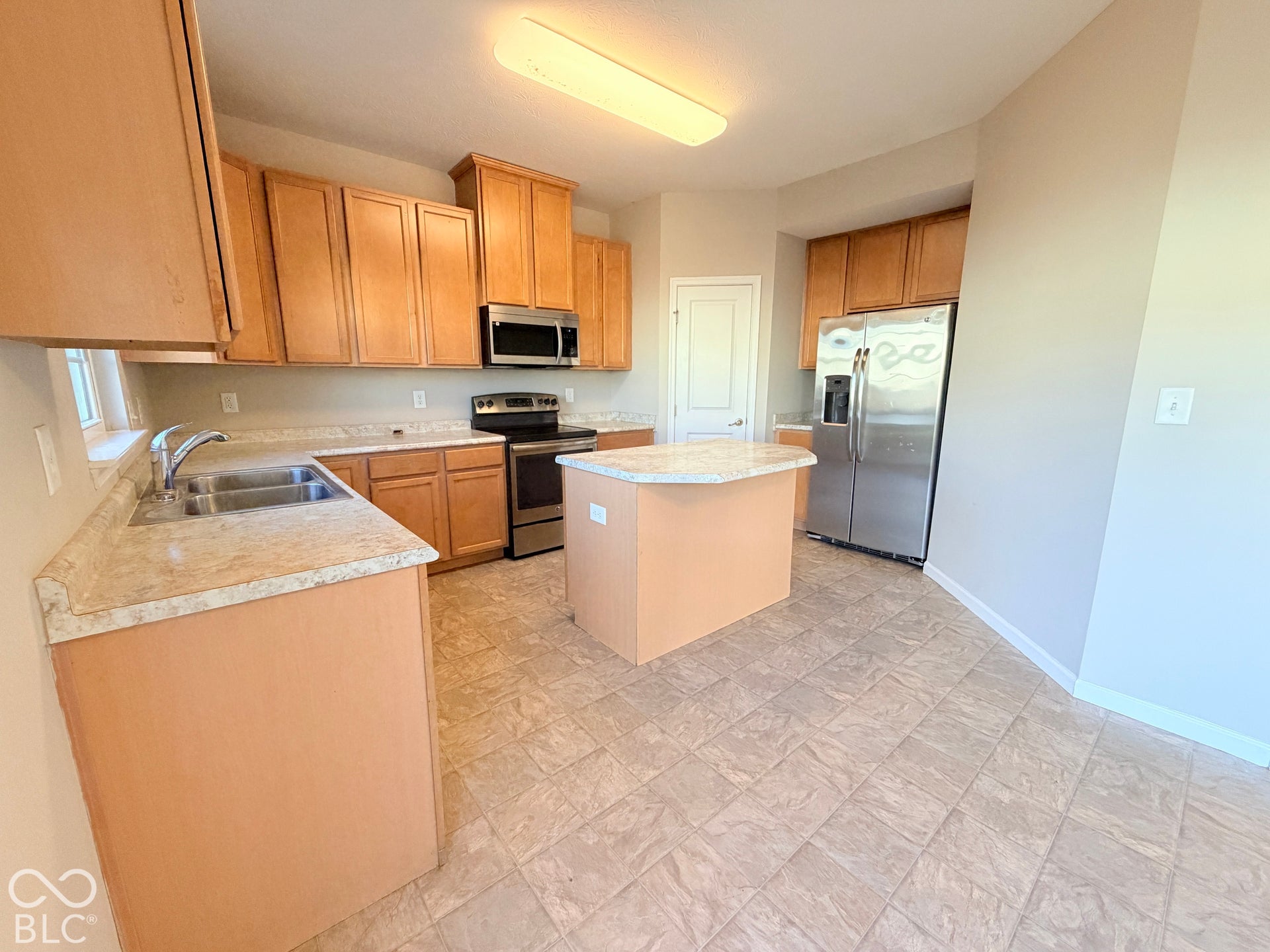 652 Classic Lane, Greenwood, IN 46143 Kitchen featuring light wood-finish cabinetry, stainless steel appliances, a central island, composite countertops, and square tile flooring
