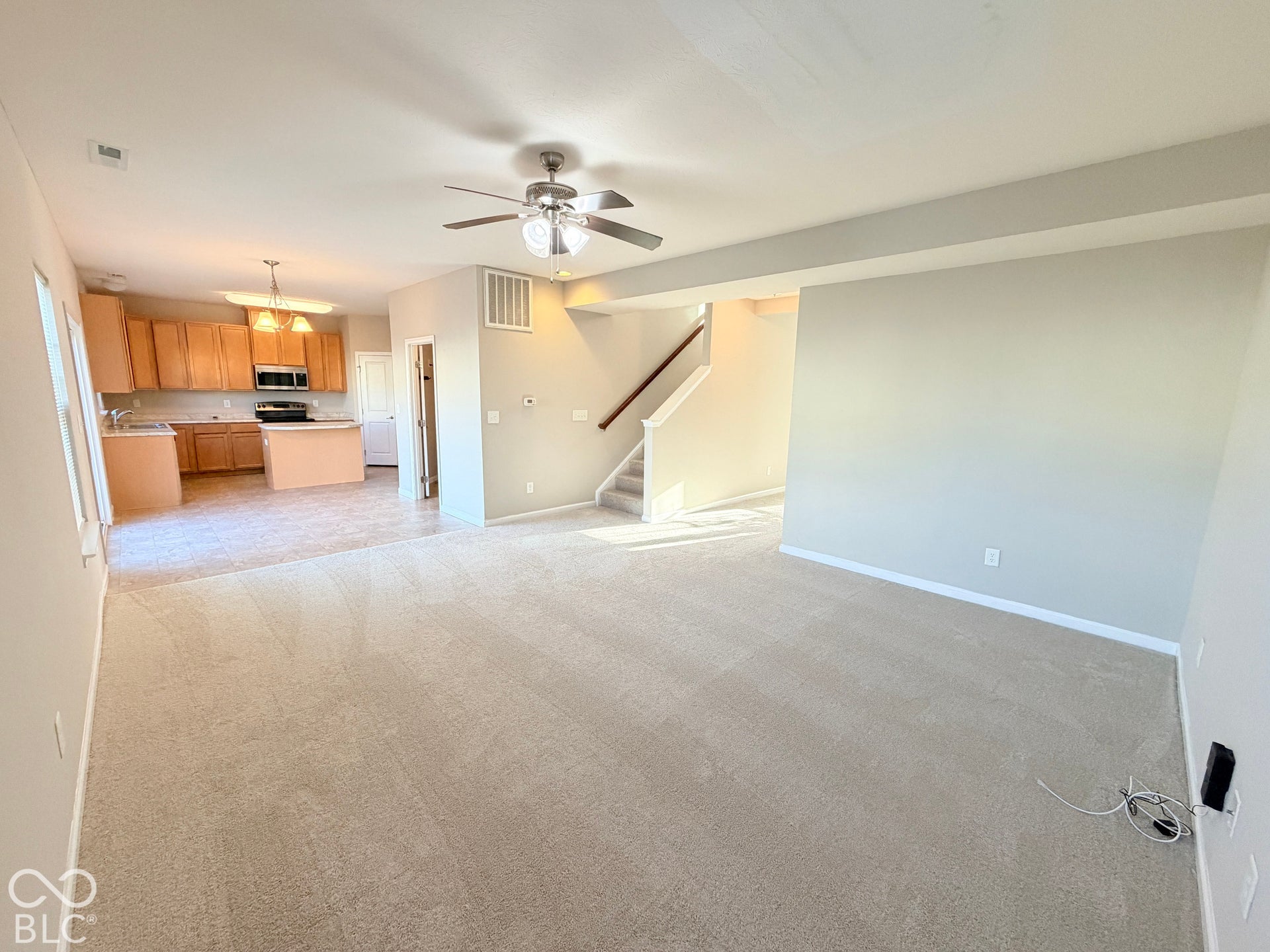 652 Classic Lane, Greenwood, IN 46143 Open-concept living area featuring light-colored carpeting, a ceiling fan, and staircase with wood handrail