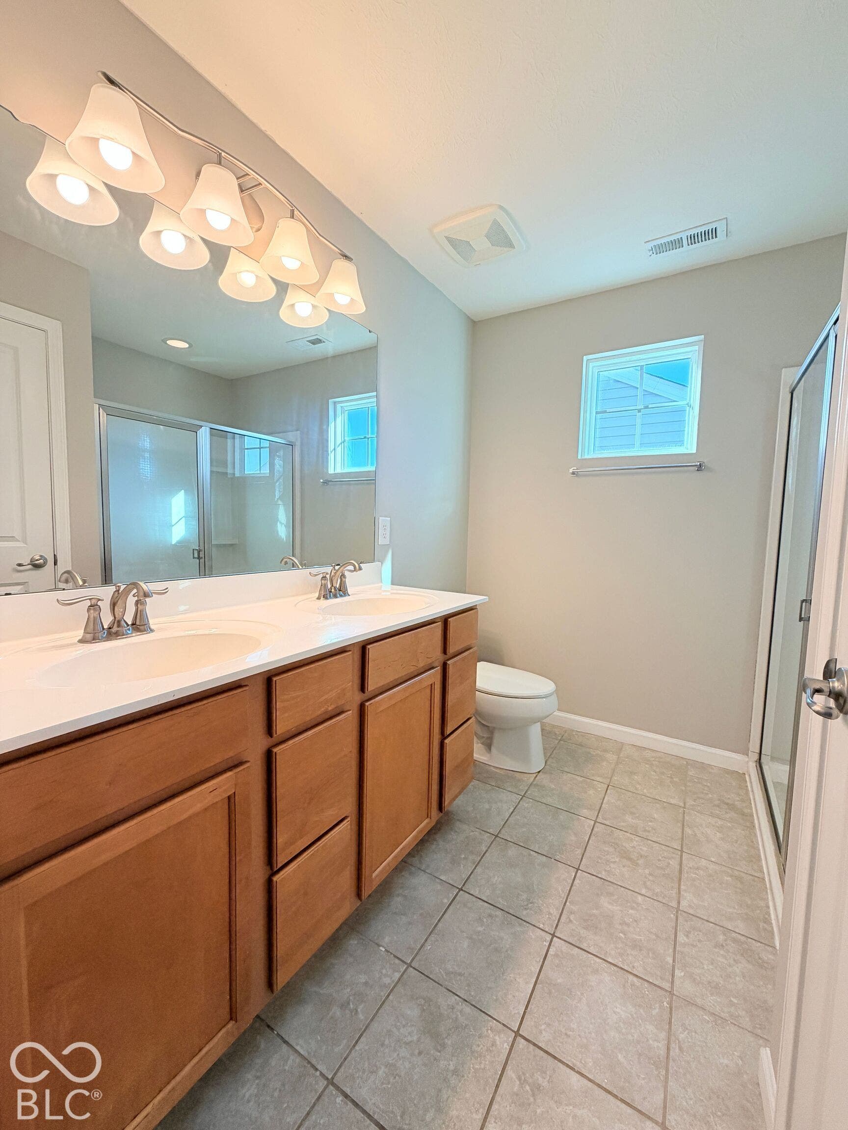 652 Classic Lane, Greenwood, IN 46143 Dual vanity with light wood-finish cabinetry, a white countertop, and brushed nickel fixtures
