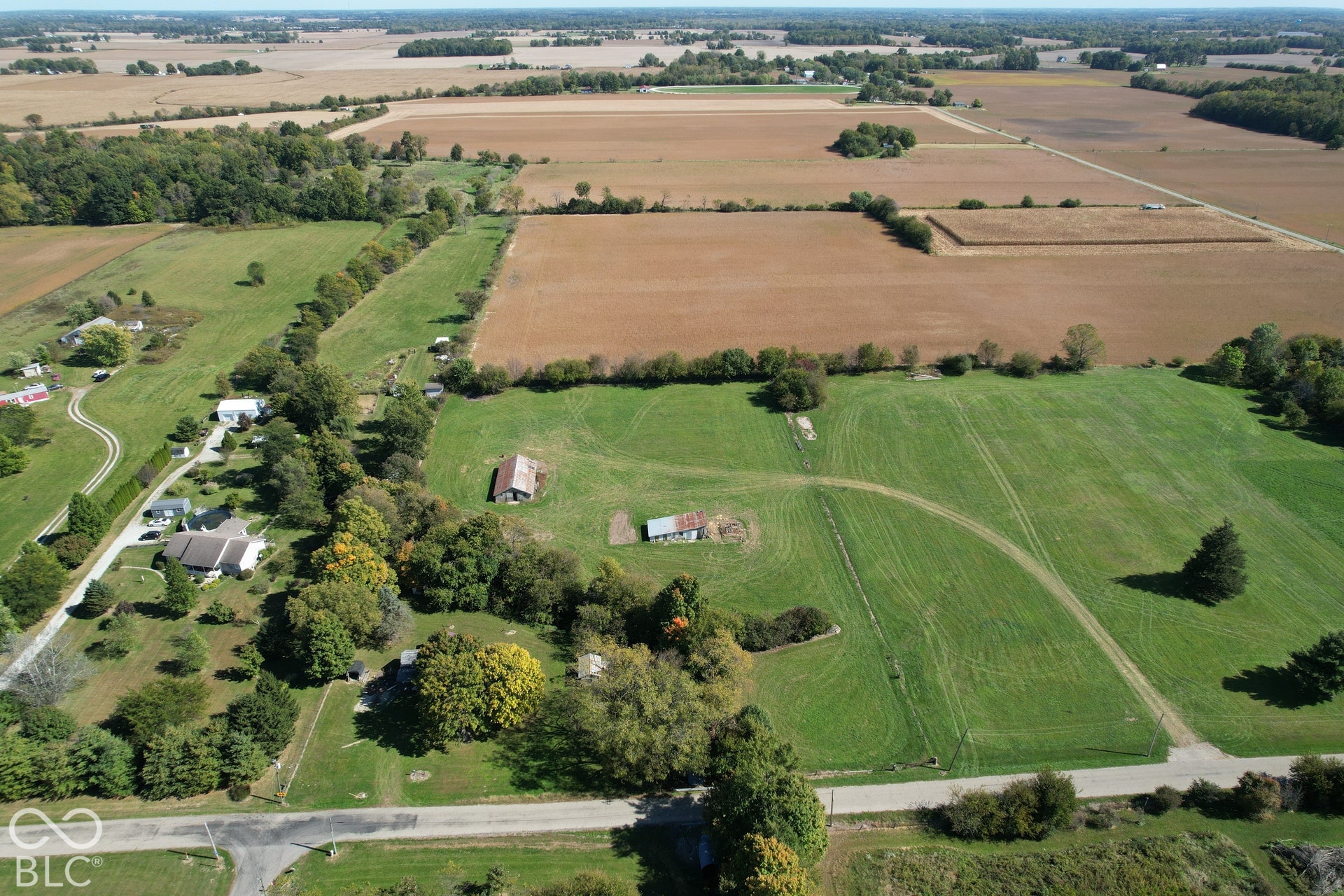 Expansive green acreage with mature trees and a distant agricultural field backdrop