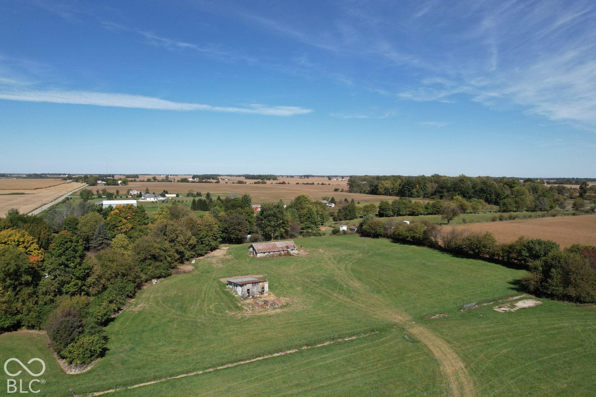 Expansive green acreage with mature trees and visible outbuildings
