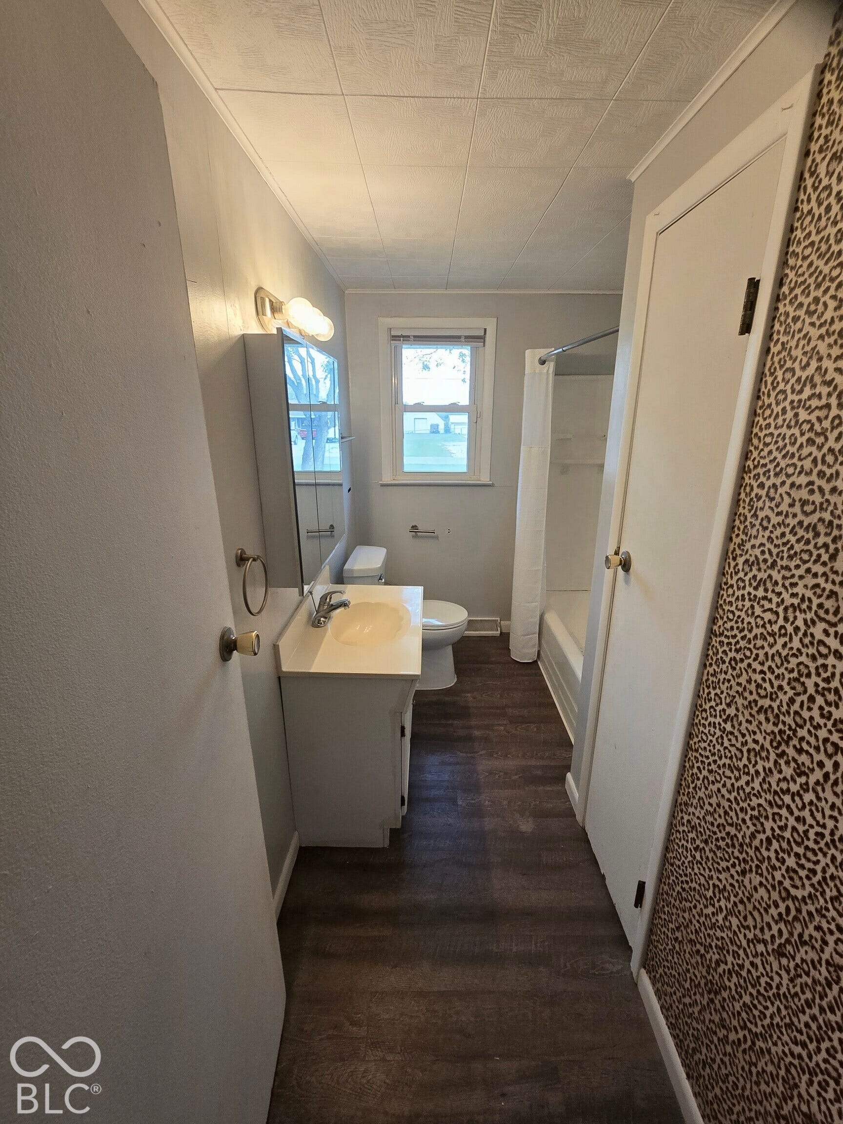 6720 S County Road 800 W, Daleville, IN 47334 Bathroom featuring a single window, white vanity with integrated sink, wood-finish flooring, and a shower-tub combination