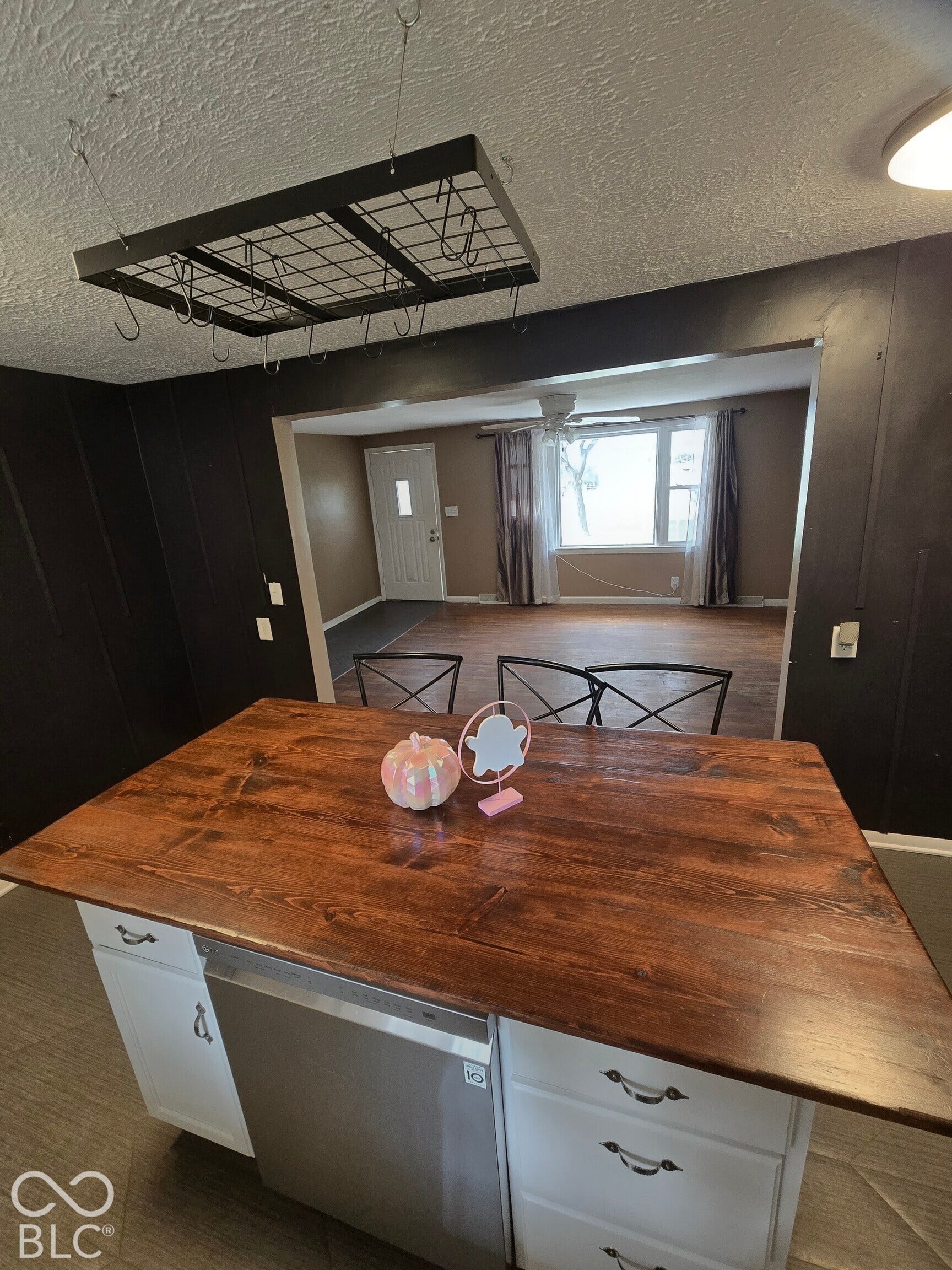 6720 S County Road 800 W, Daleville, IN 47334 Virtually Altered - Kitchen island with a rich wood-finish countertop, white cabinetry, and a stainless steel dishwasher