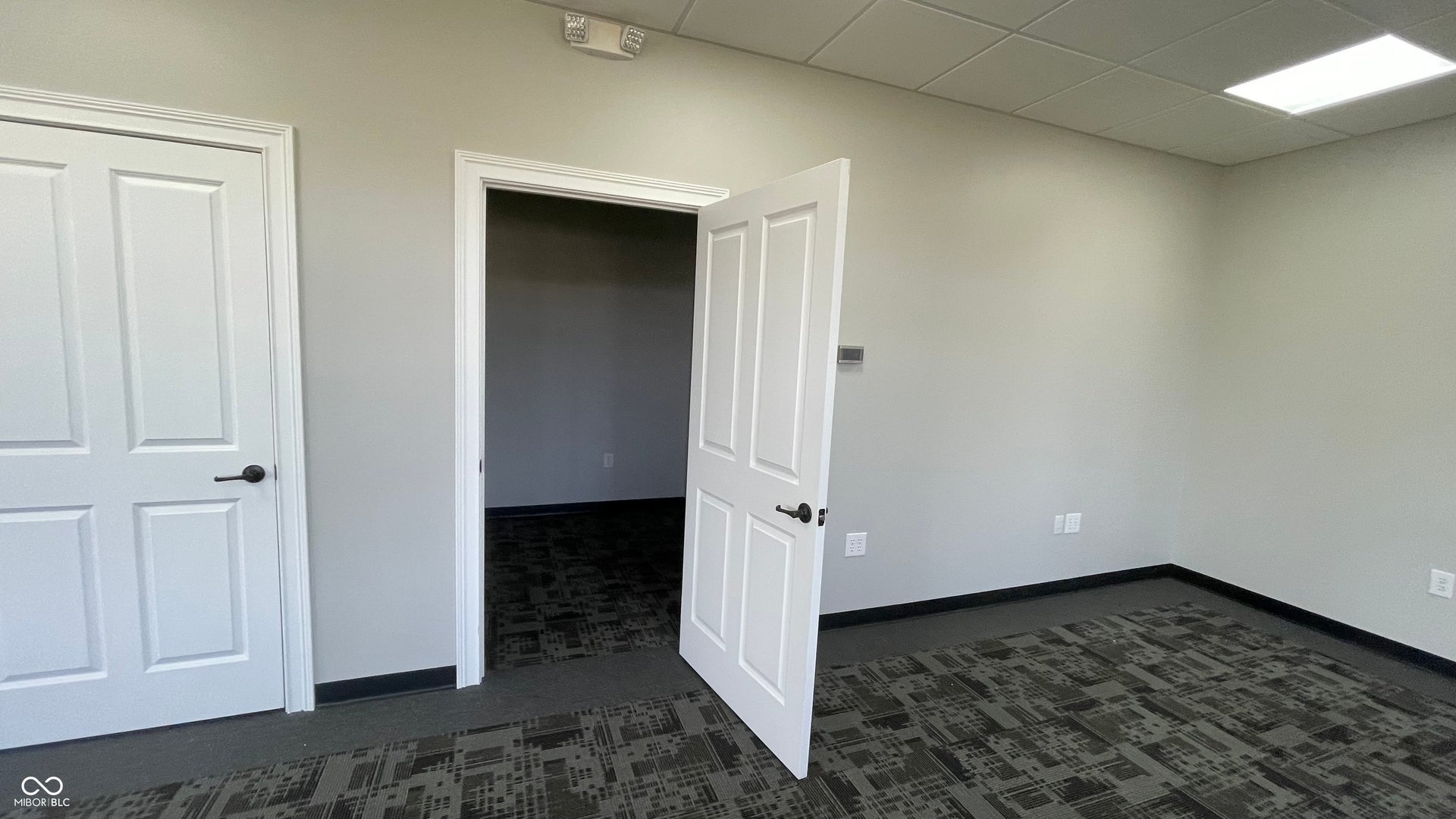 unfurnished bedroom featuring a paneled ceiling and dark colored carpet