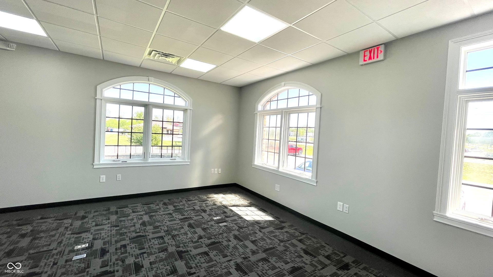 unfurnished room featuring dark colored carpet, a paneled ceiling, and healthy amount of natural light
