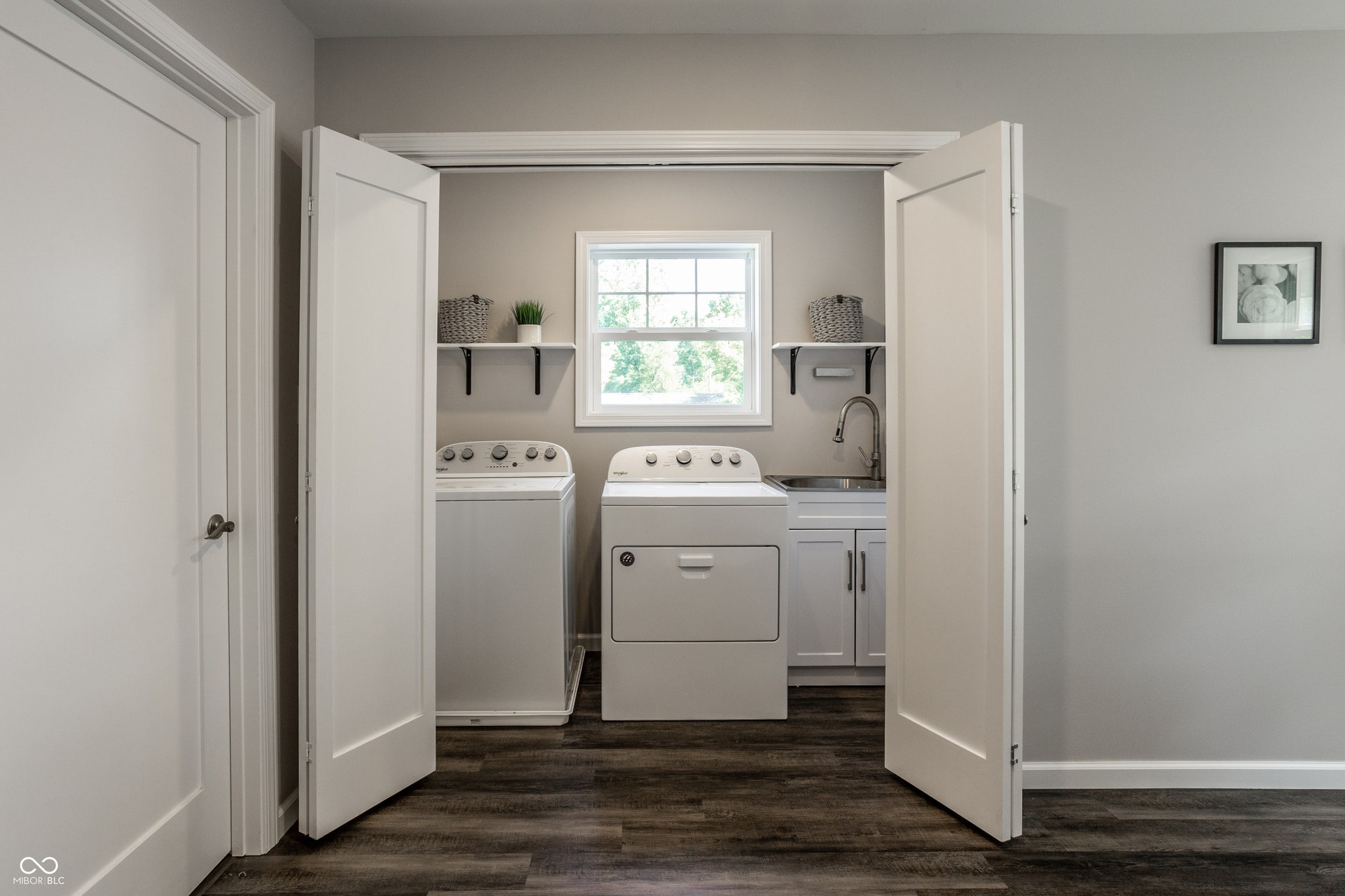 2323 E 57th Street, Indianapolis, IN 46220 Dedicated laundry area featuring wood-finish flooring, a utility sink with a gooseneck faucet, white cabinetry, and two wall-mounted shelves
