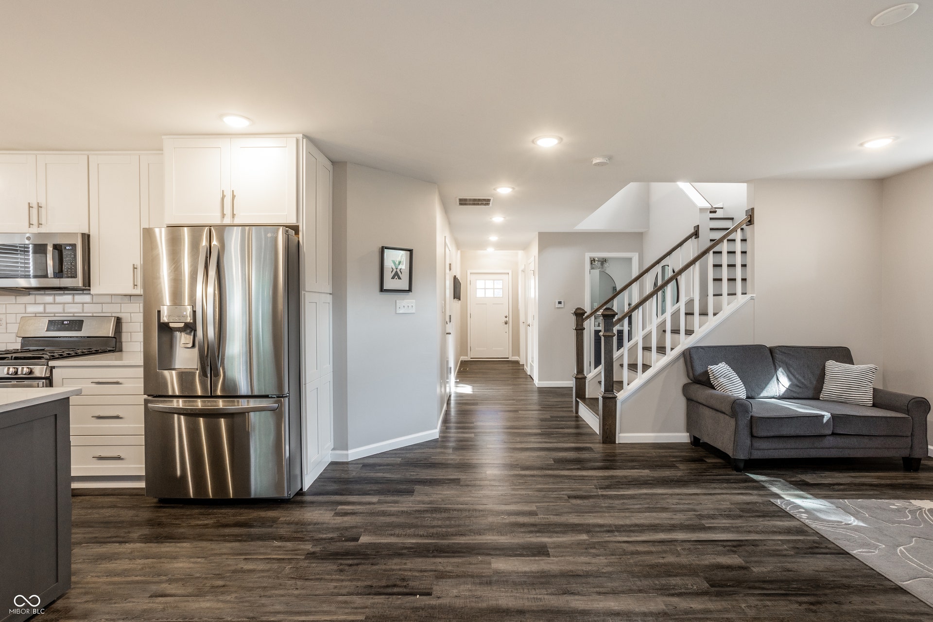 2323 E 57th Street, Indianapolis, IN 46220 Wood-finish flooring throughout, kitchen with stainless steel appliances, white cabinetry, and subway tile backsplash