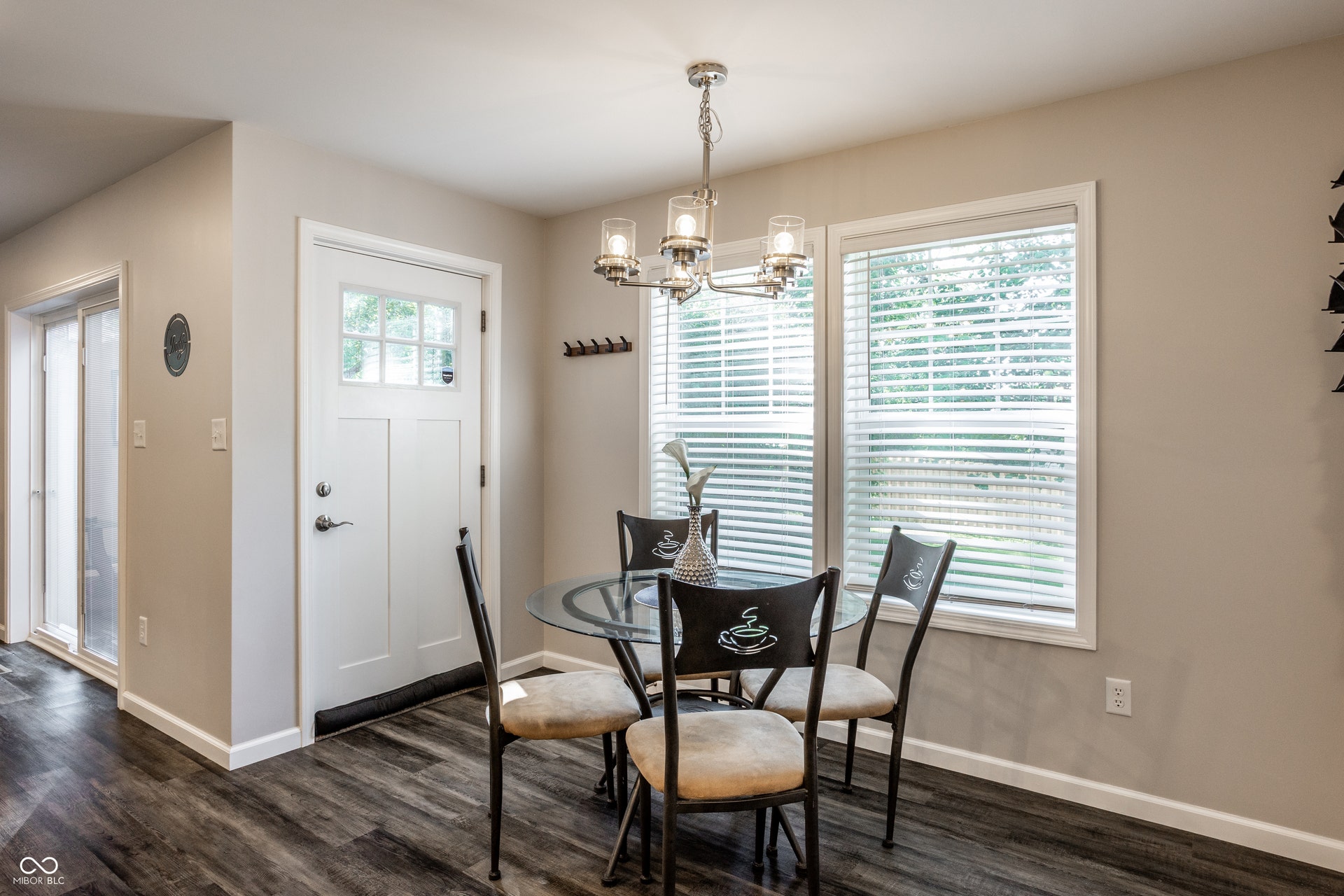2323 E 57th Street, Indianapolis, IN 46220 Wood-finish flooring, white paneled door with glass inserts, dual windows with blinds, and a polished chrome chandelier