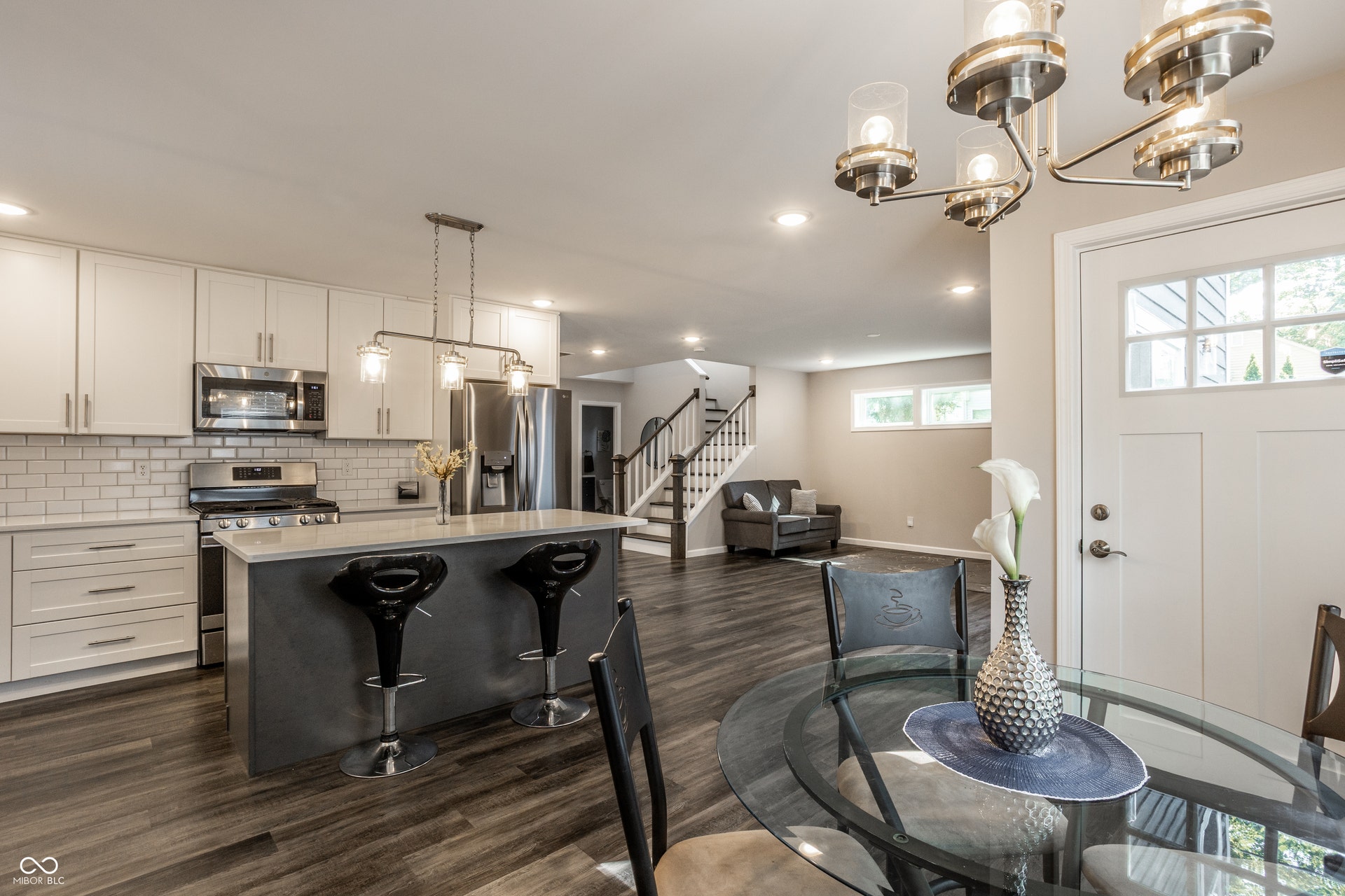 2323 E 57th Street, Indianapolis, IN 46220 Kitchen featuring white shaker cabinetry, stainless steel appliances, a subway tile backsplash, and a central island with bar seating