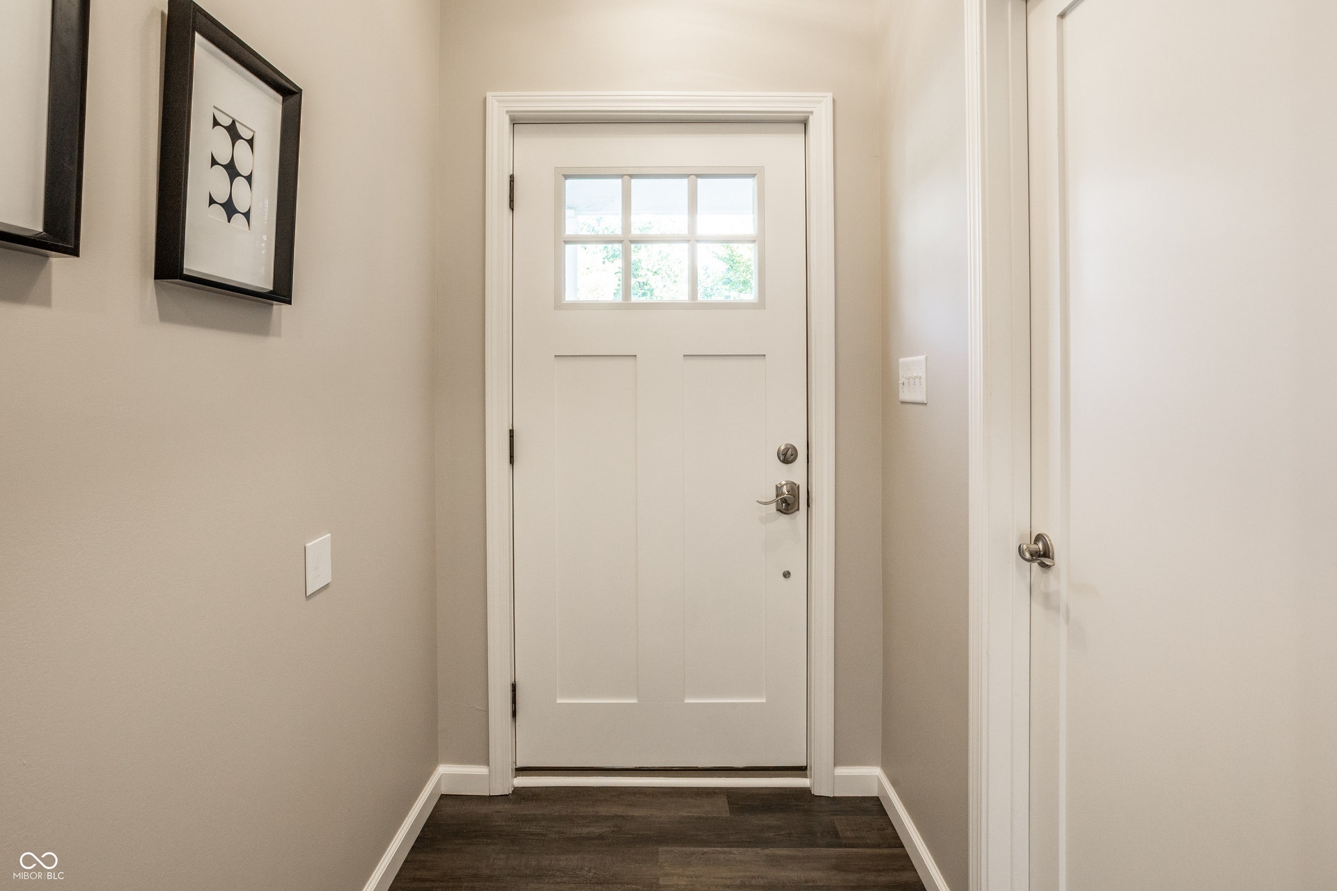 2323 E 57th Street, Indianapolis, IN 46220 Welcoming foyer featuring a classic six-panel entry door with transom window, dark wood-finish flooring, and neutral wall finishes