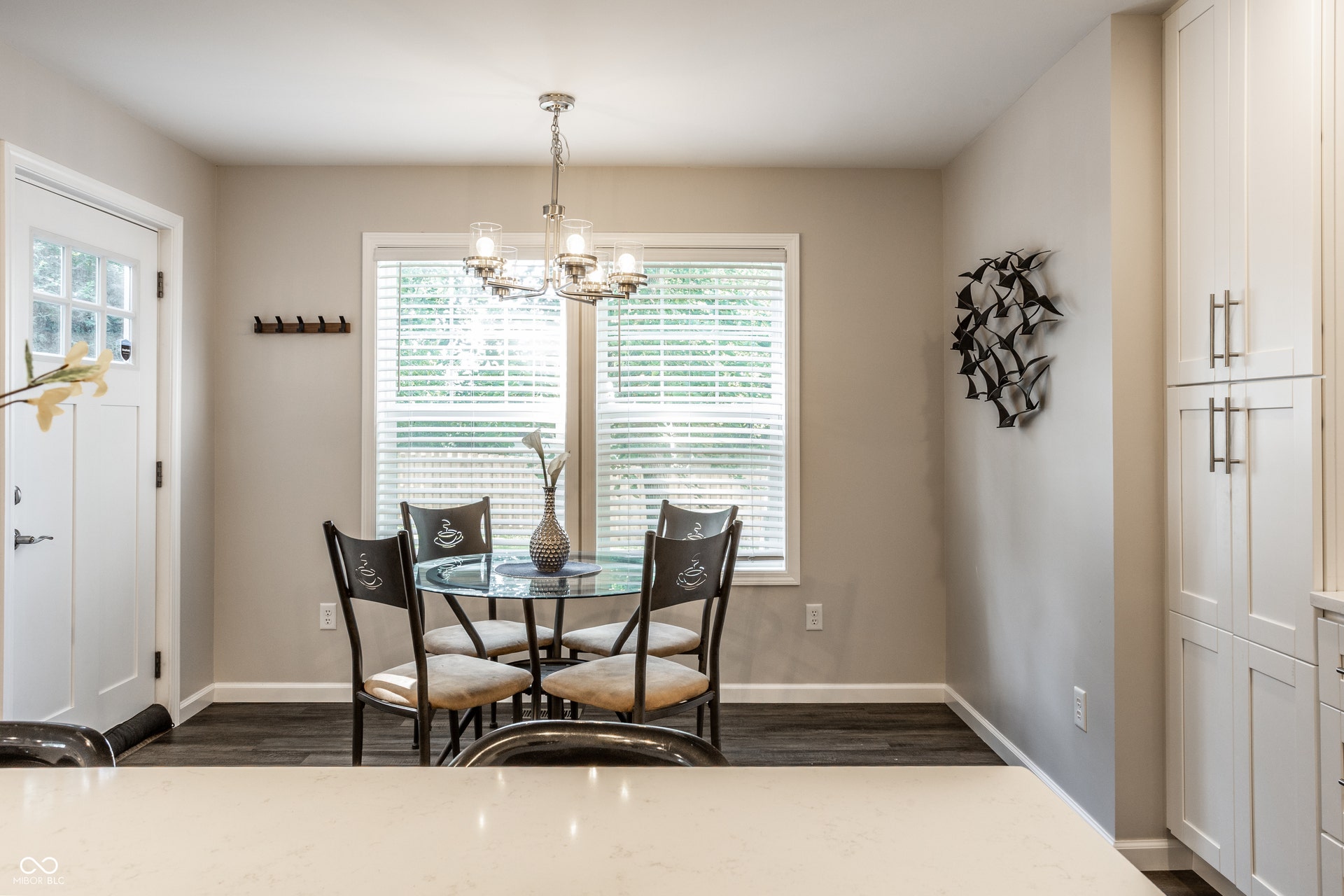 2323 E 57th Street, Indianapolis, IN 46220 Bright dining area featuring large transom windows with plantation shutters, polished light-finish flooring, a chrome pendant light fixture, and white painted cabinetry
