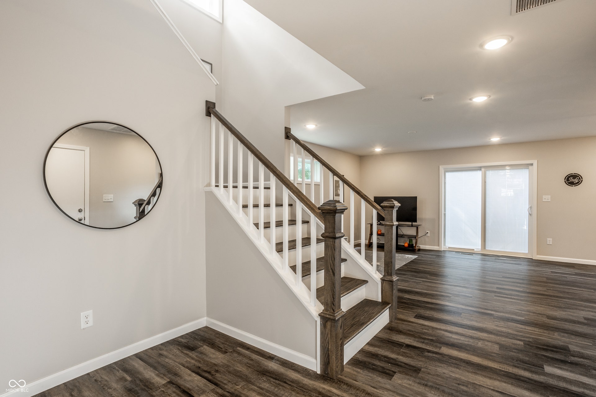 2323 E 57th Street, Indianapolis, IN 46220 Staircase featuring wood-finish treads and white risers, white balusters with dark wood-finish handrails, wood-finish flooring, recessed ceiling lighting, and sliding glass doors