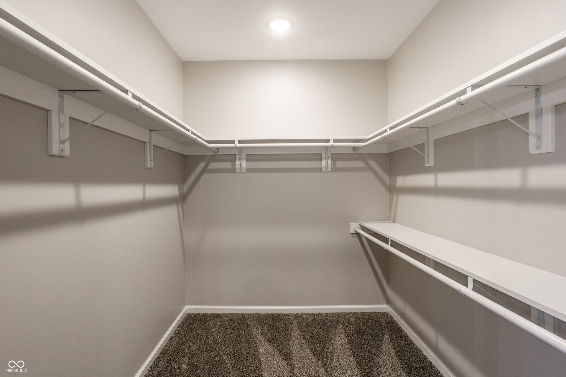 2323 E 57th Street, Indianapolis, IN 46220 Spacious walk-in closet featuring custom built-in shelving and hanging rods with integrated LED lighting, neutral wall finishes, and carpeted flooring for comfort and organization